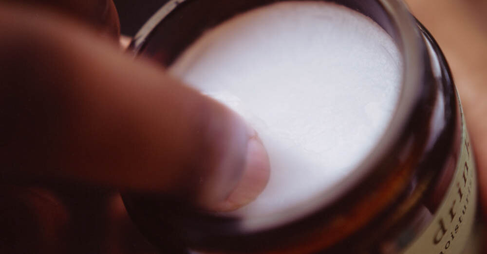 a finger scooping CBD coconut oil out of a jar
