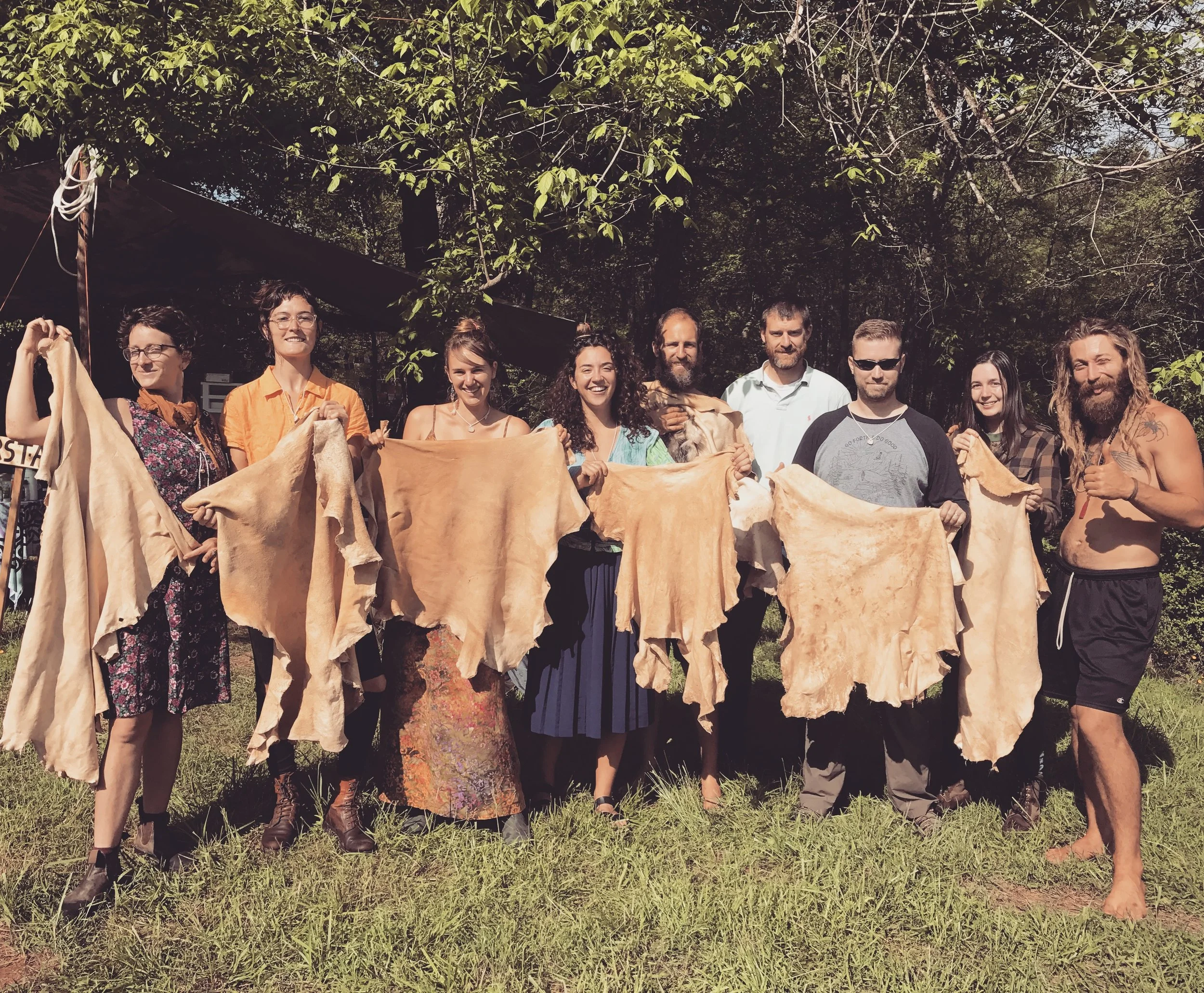 Workshop participants showing the buckskin pieces they created from deer hide