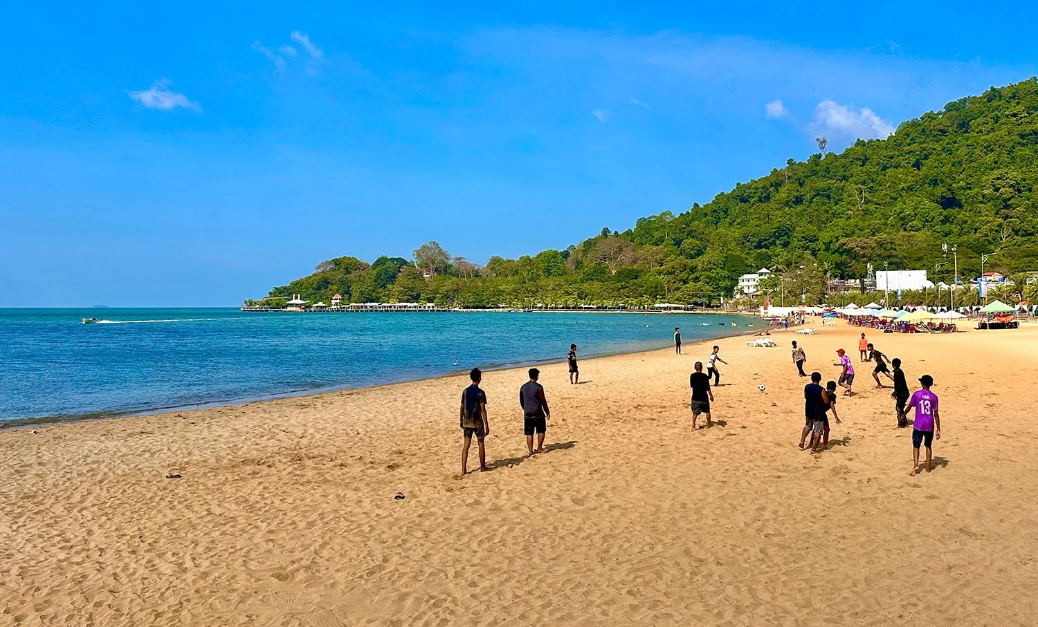 Young men playing soccer on a yellow sandy beach under a blue sky at Kep in southern Cambodia.