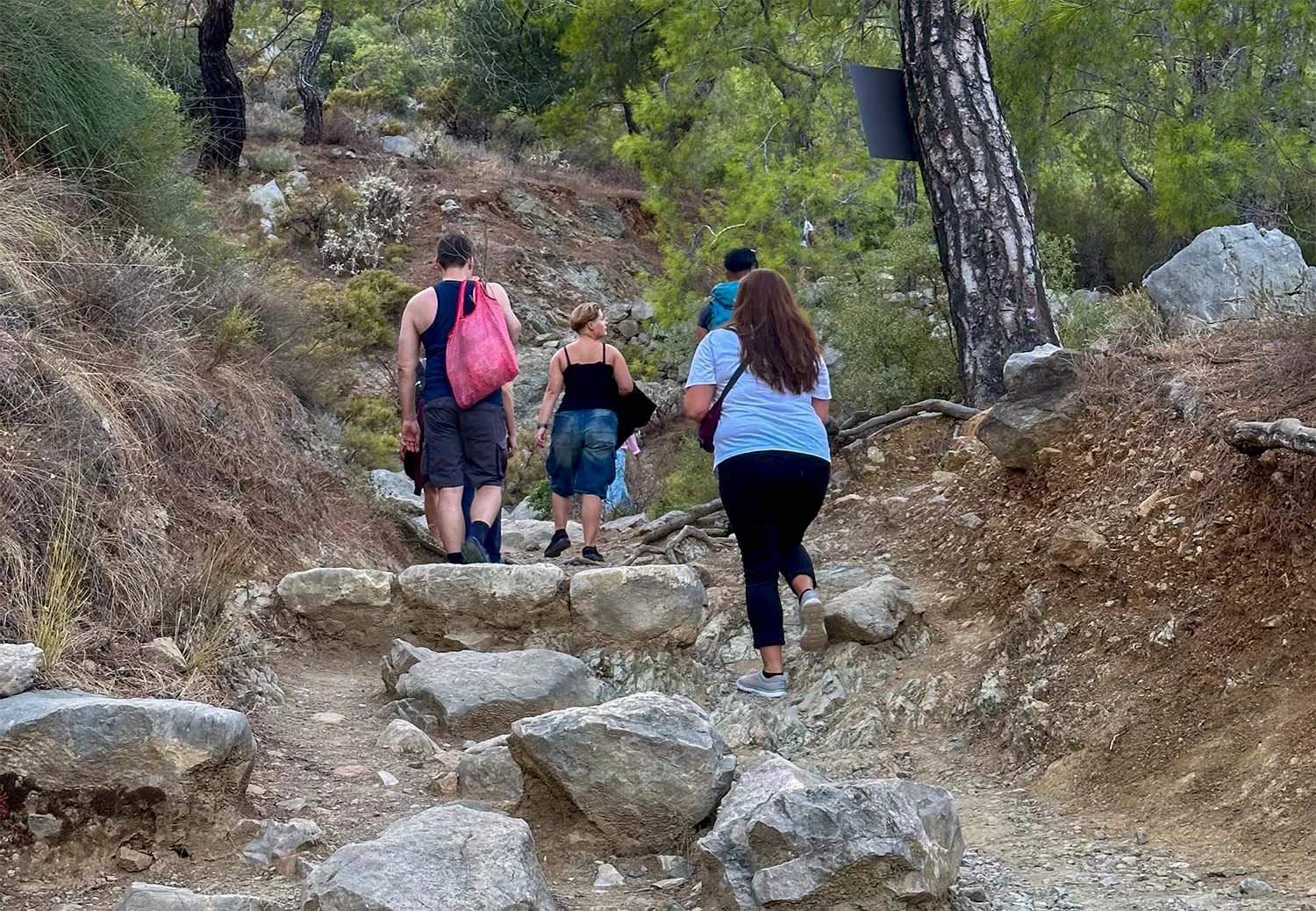 Four tourists walking up a rocky trail on Mount Chimaera, Antalya, Türkiye.