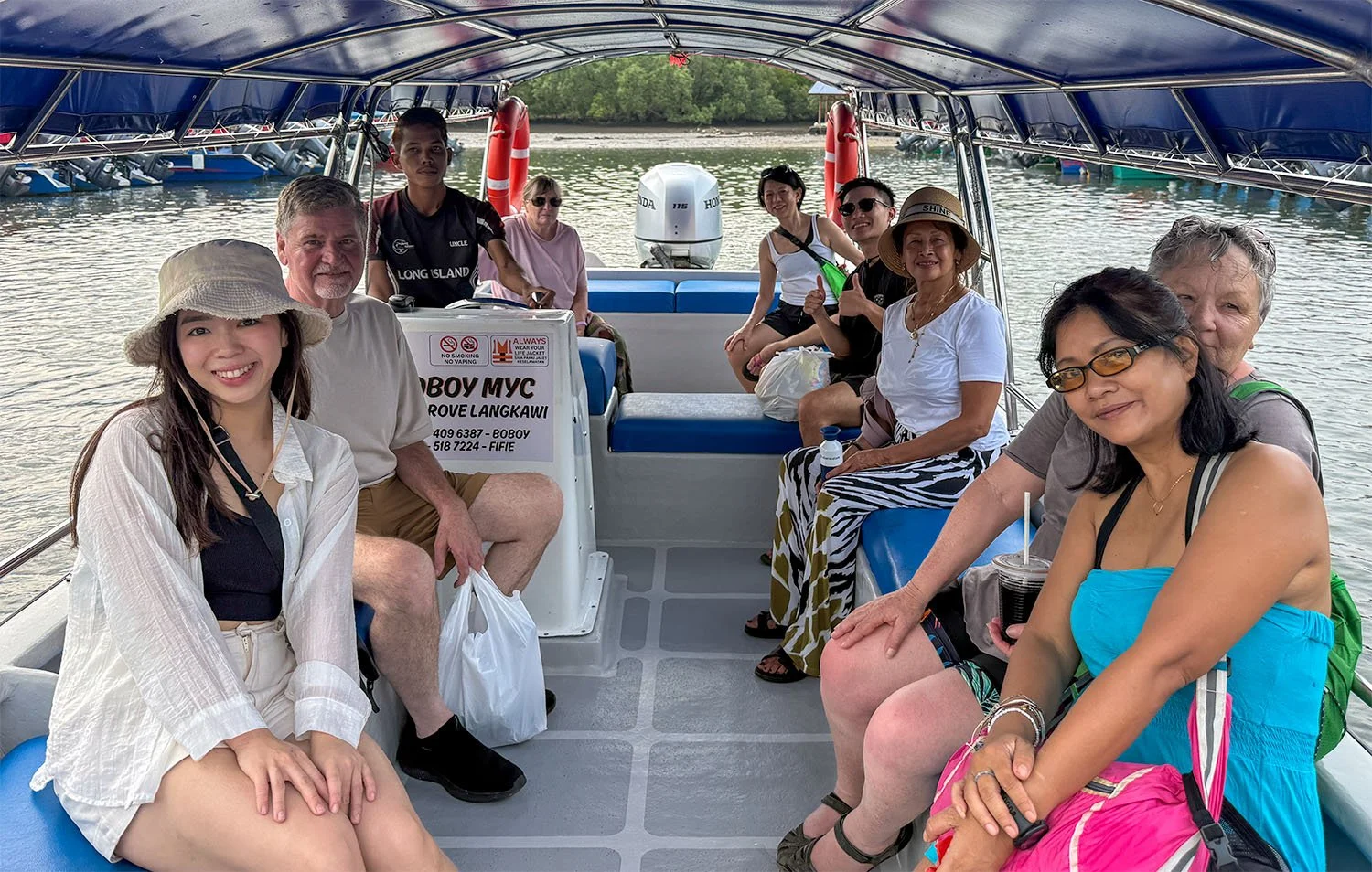 A group of eight tourists on a boat trip at Langkawi Island, Malaysia.