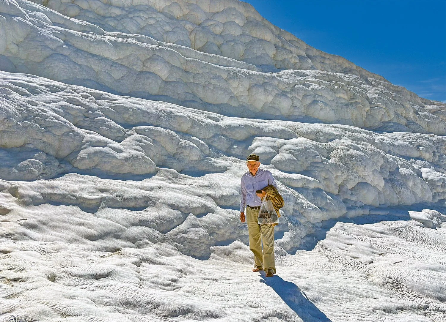 Wide view of clean and quiet mid-level terraces with only one tourist in sight at the Pamukkale Travertine Terraces in Turkey that look like snowfields.