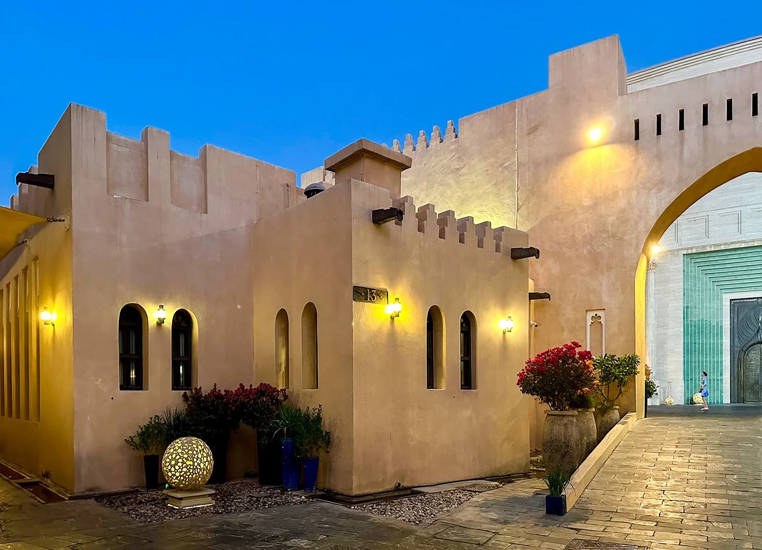Traditional buildings with a large archway at the Katara Cultural Village in Doha, Qatar, in fading light after sunset..
