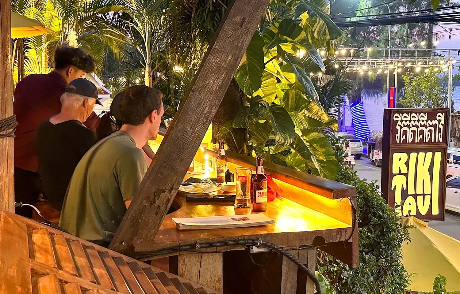Tourists eating at Rikitikitavi restaurant on Riverside Road, Kampot, Cambodia, whilst looking out to the river on the other side of the road.