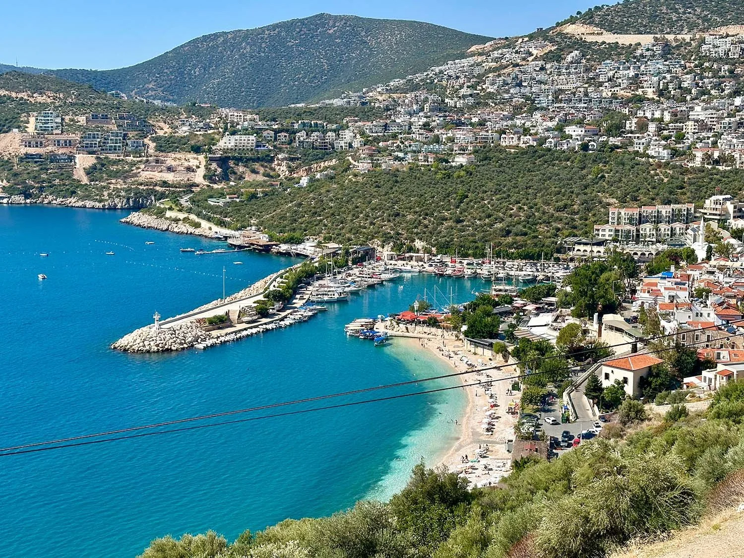 View of the Turkish Riviera resort town of Kalkan and its port seen from a road on the hills above the town.