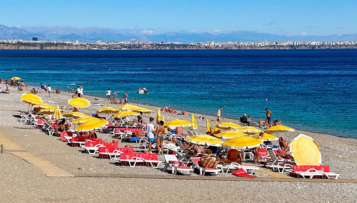 Tourists on sunbeds and under sun umbrellas on Konyaalti Beach at Antalya on the Turkish Riviera.