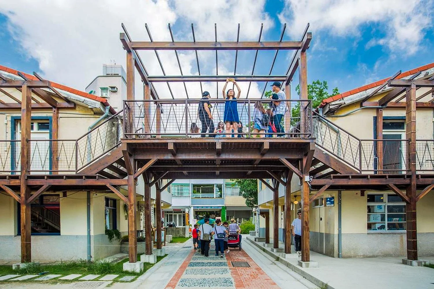 Exterior view of Shen Ji New Village in Taichung, Taiwan, with shoppers on the lower level and tourists taking selfies on an upper level.