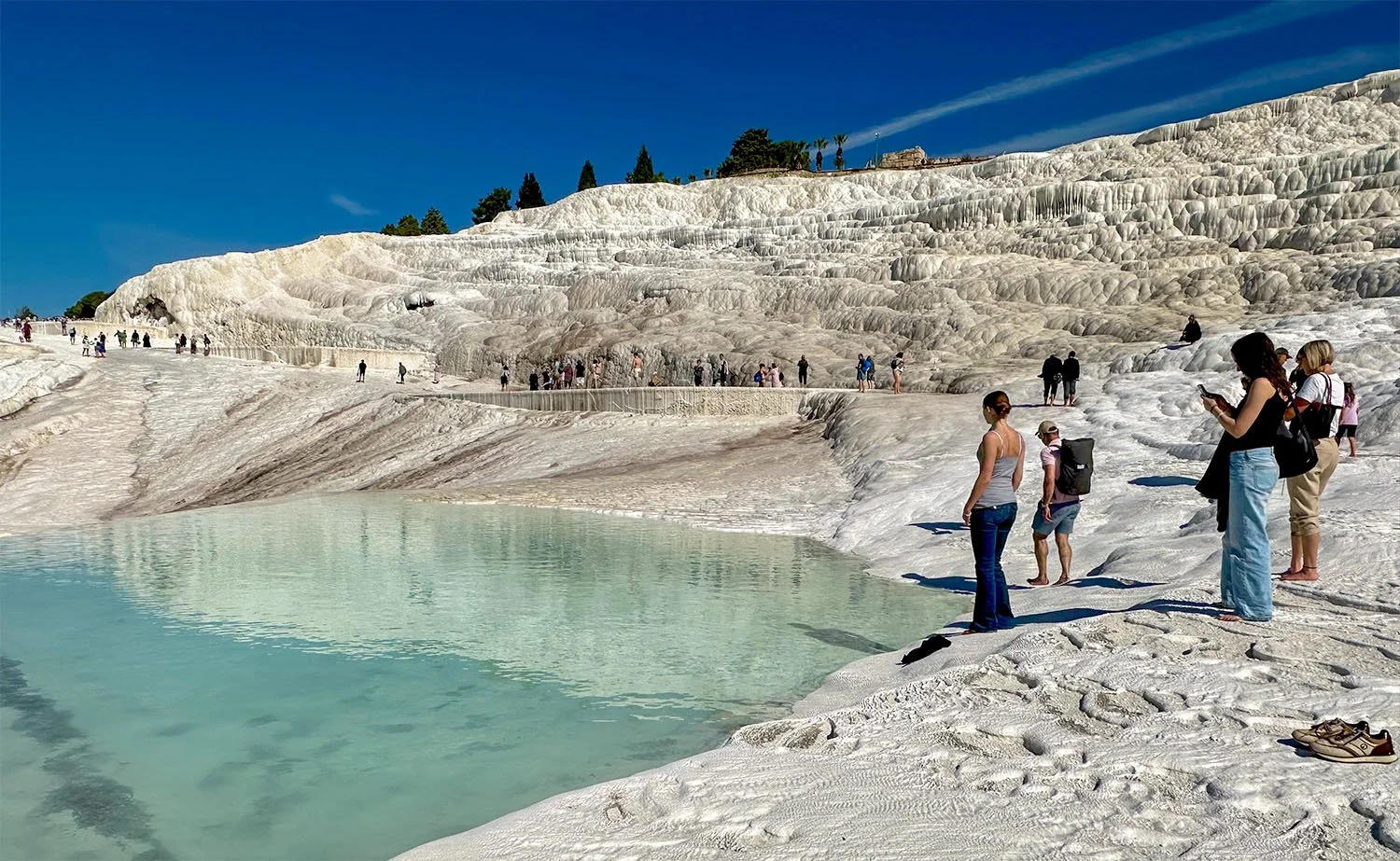 View of dozens of tourists on the upper terraces of the Pamukkale Travertine Terraces in Turkiye.