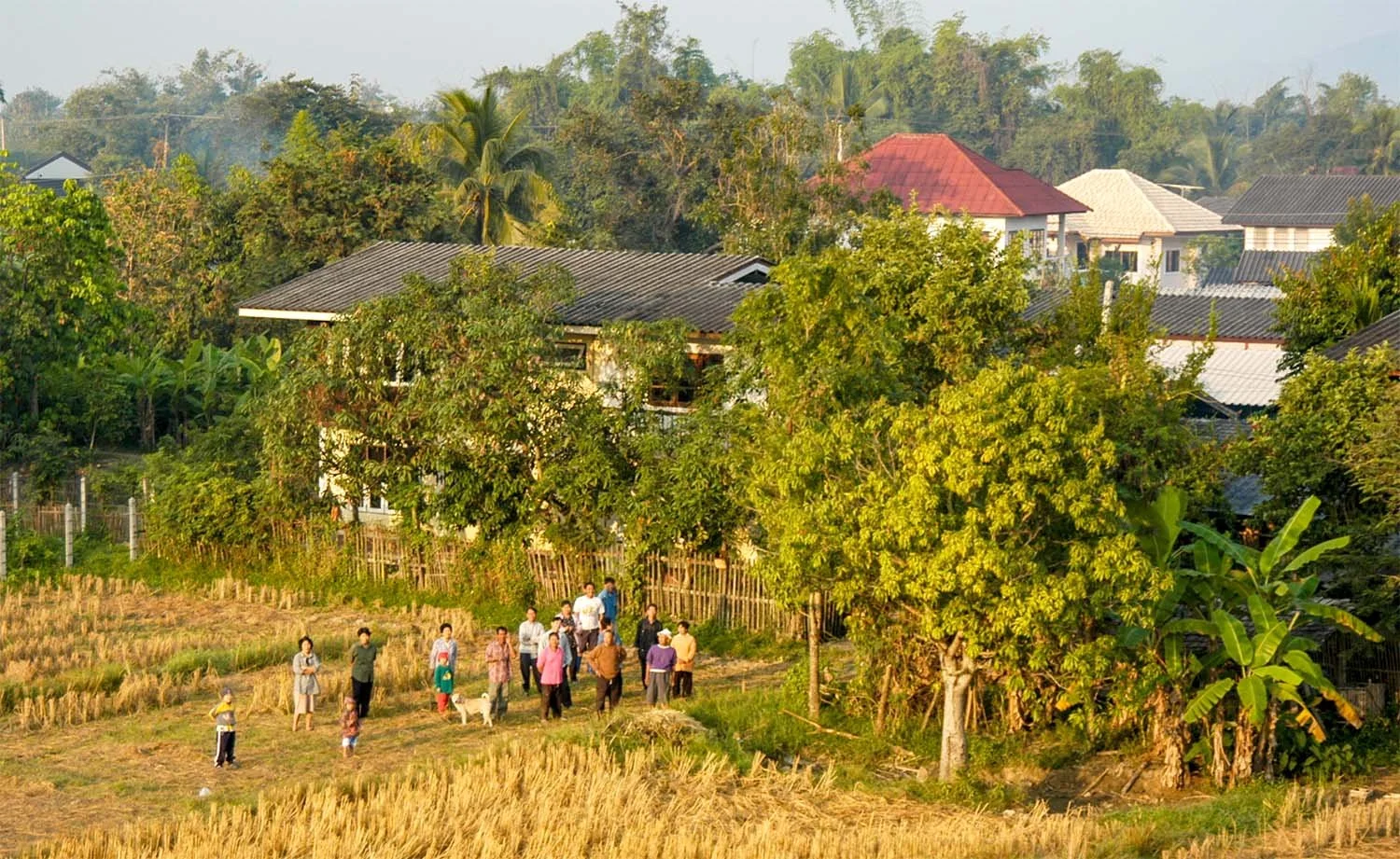 Rural villagers near Chiang Mai, Thailand, look up to a hot air balloon floating past at low altitude in the early morning.