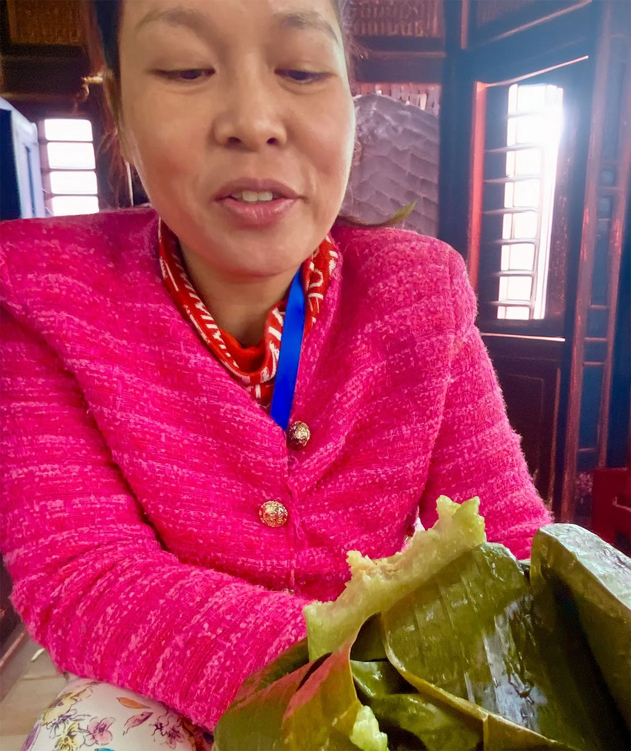 Woman eating a Tet cake inside a traditional Vietnamese house.