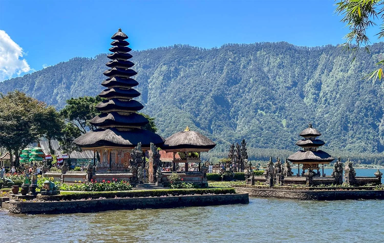 View of the lakeside Ulun Danu Beratan Temple. in northern Bali with forested mountains in the background.