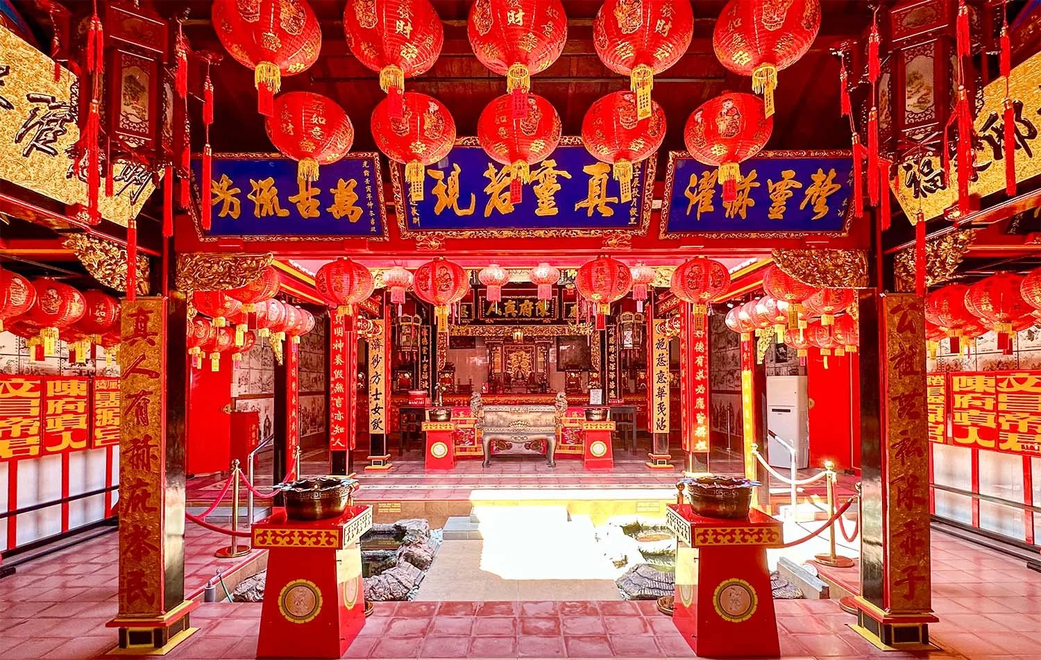 A view of the colourful interior of the Gwan Kiong Chinese temple in Singaraja, North Bali, showing the intricate red and gold carvings of the well-maintained structure.