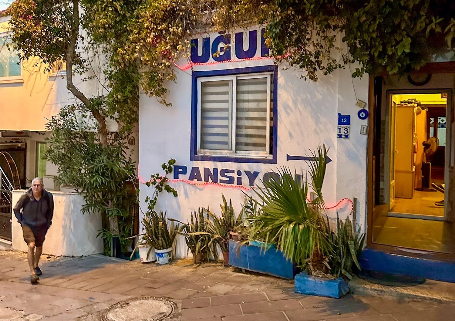 A man walks past a pansiyon (guest house) on a narrow street in Bodrum, Türkiye.