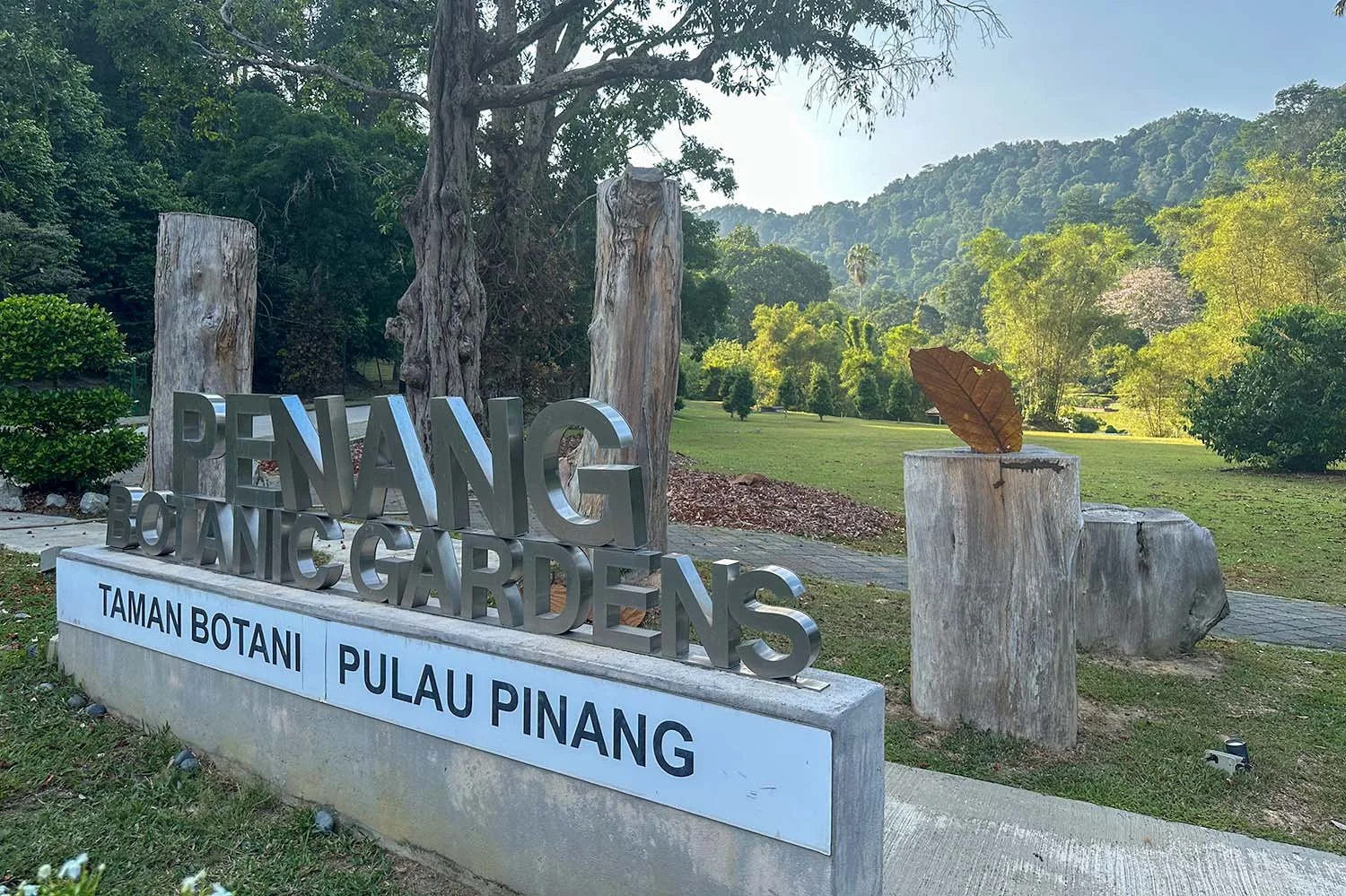 View of the Penang Botanic Gardens with a large name sign in the foreground.