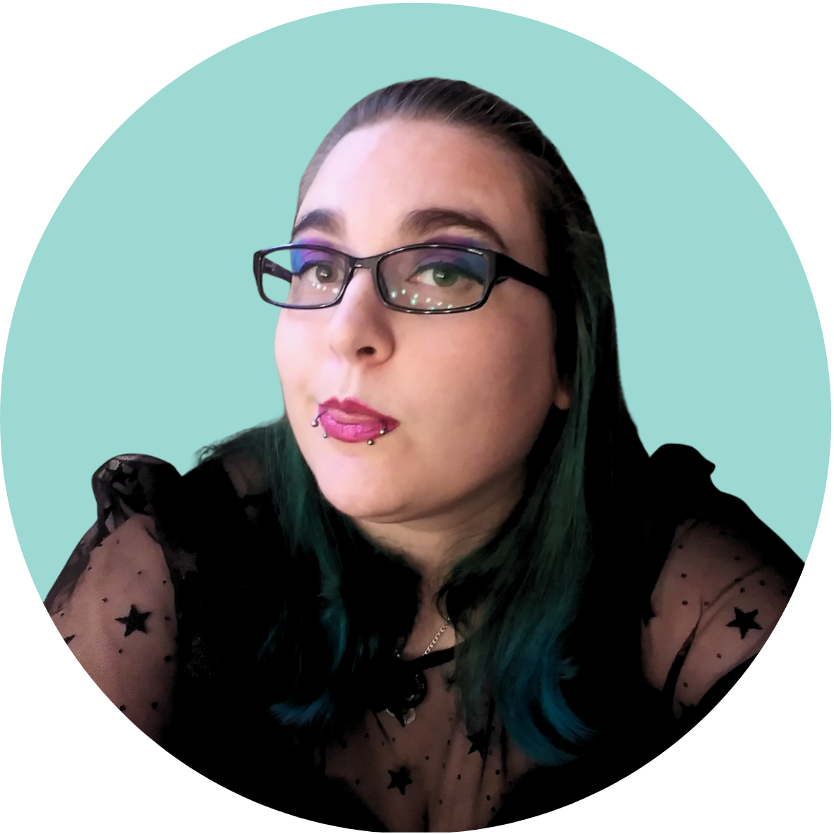 A woman with glasses and dark hair with teal tips, wearing a black sheer top with star patterns, holding a microphone, against a light teal circular background.