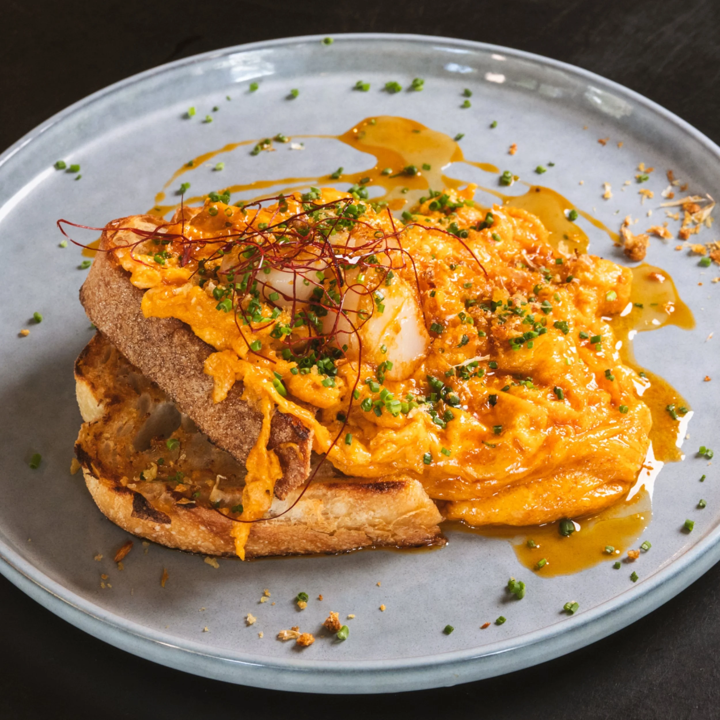 Spicy scallop scrambled eggs with chilli oil on sourdough at ALL DAY café in West End Brisbane