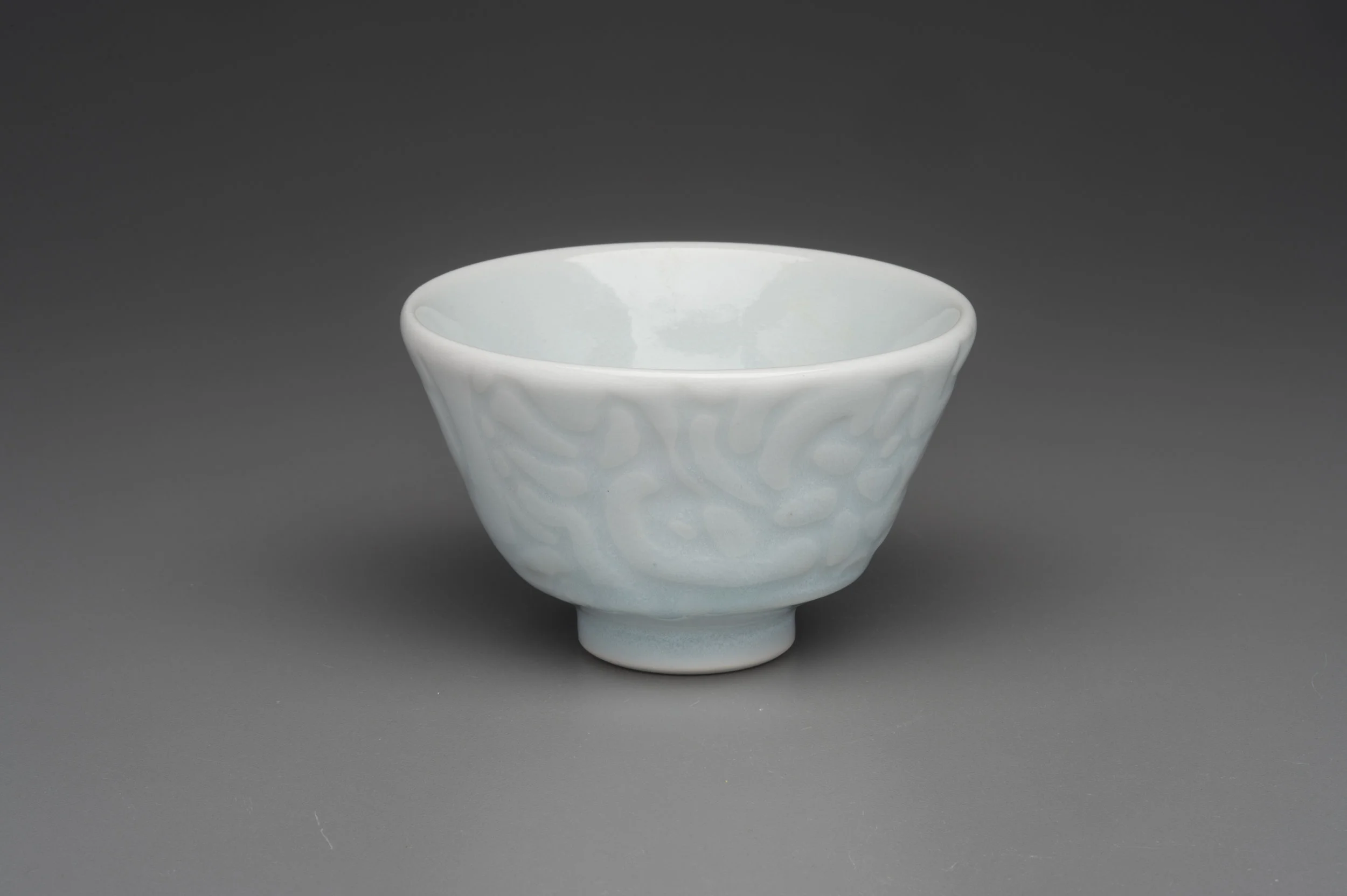Water etched porcelain tea cup with celadon glaze