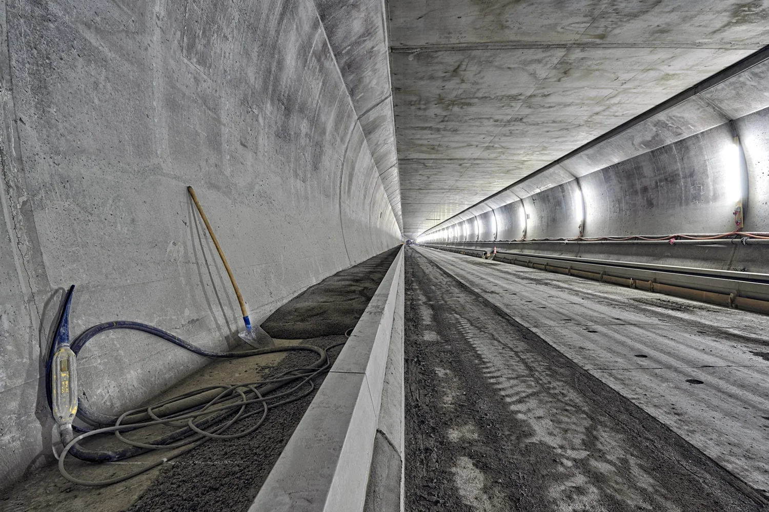 Die Verkleidung und die Zwischendecke der Hauptröhre sind bereits fertig erstellt. Nun finden die Bankettarbeiten seitlich der Fahrbahn statt. Dazu werden als Fahrbahnabschluss vorgefertigten Randsteine versetzt und der dahinterliegende Bereich mit Beton vergossen.
