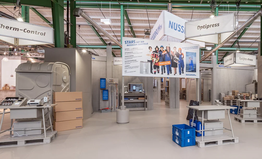 Die R. Nussbaum AG stellt Armaturen und Systeme im Trinkwasserbereich her. Unter dem Motto «Mach’s vor Ort» präsentierte die Firma auf einer inszenierten Baustelle auf der Swissbau 2018 ihre Produkte. Fachleute konnten selbst Hand anlegen und das Vorwandsystem Optivis sowie weitere Produkte im Bereich der Sanitär- und Heiztechnik ausprobieren. Auf einer grossen Bautafel schilderte die Komödiantin Anet Corti in den Rollen als Planerin, Buchhalterin, Chefmonteurin und Feuerwehrfrau die Arbeit mit dem Vorwandsystem Optivis.
