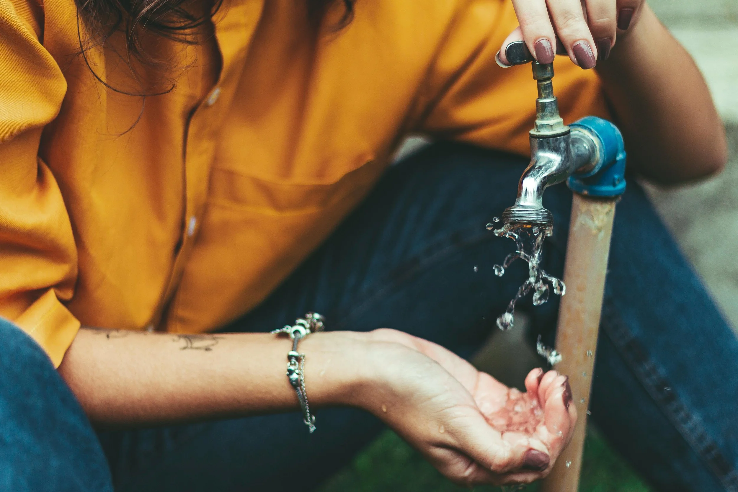 Person holding their hand below a water spigot