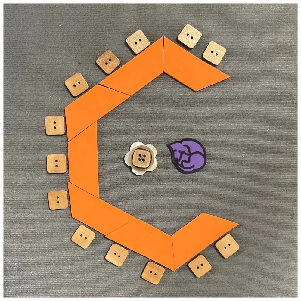 Orange tables angled around to make a c-shape configuration. Chairs around the outside of the "C" and icons representing a rolling chair and guide dog in the center of the c-shape.