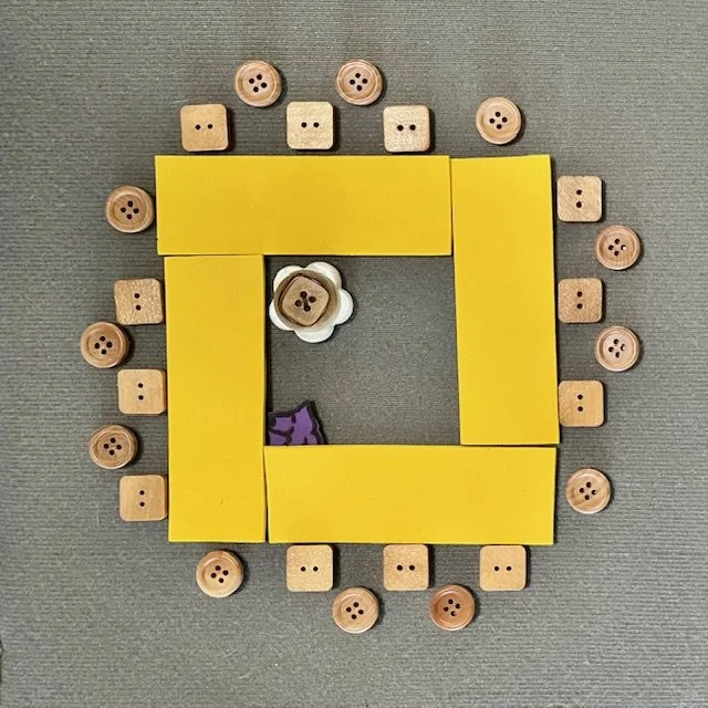 Yellow rectangles represent tables, configured in a hollow square. Square icons represent people seated in chairs, placed around the tables. Round icons represent standing people staggered behind the chairs. A rolling chair is in the center.