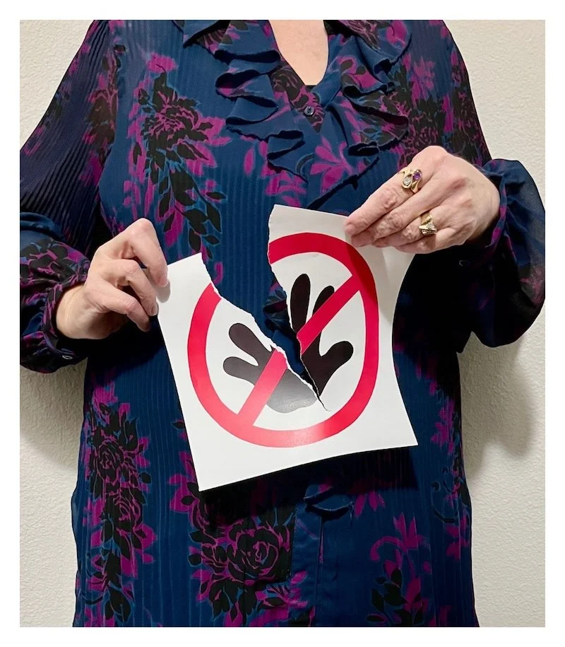 A pair of hands are tearing a Do Not Touch sign in half.