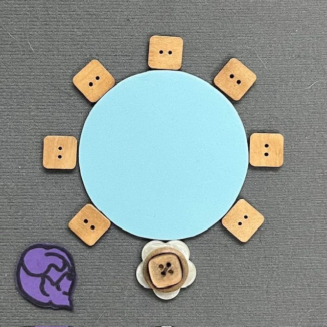 A blue circle represents a large round table. Chairs are place around the edge of the table. Icons represent a rolling chair and a guide dog.