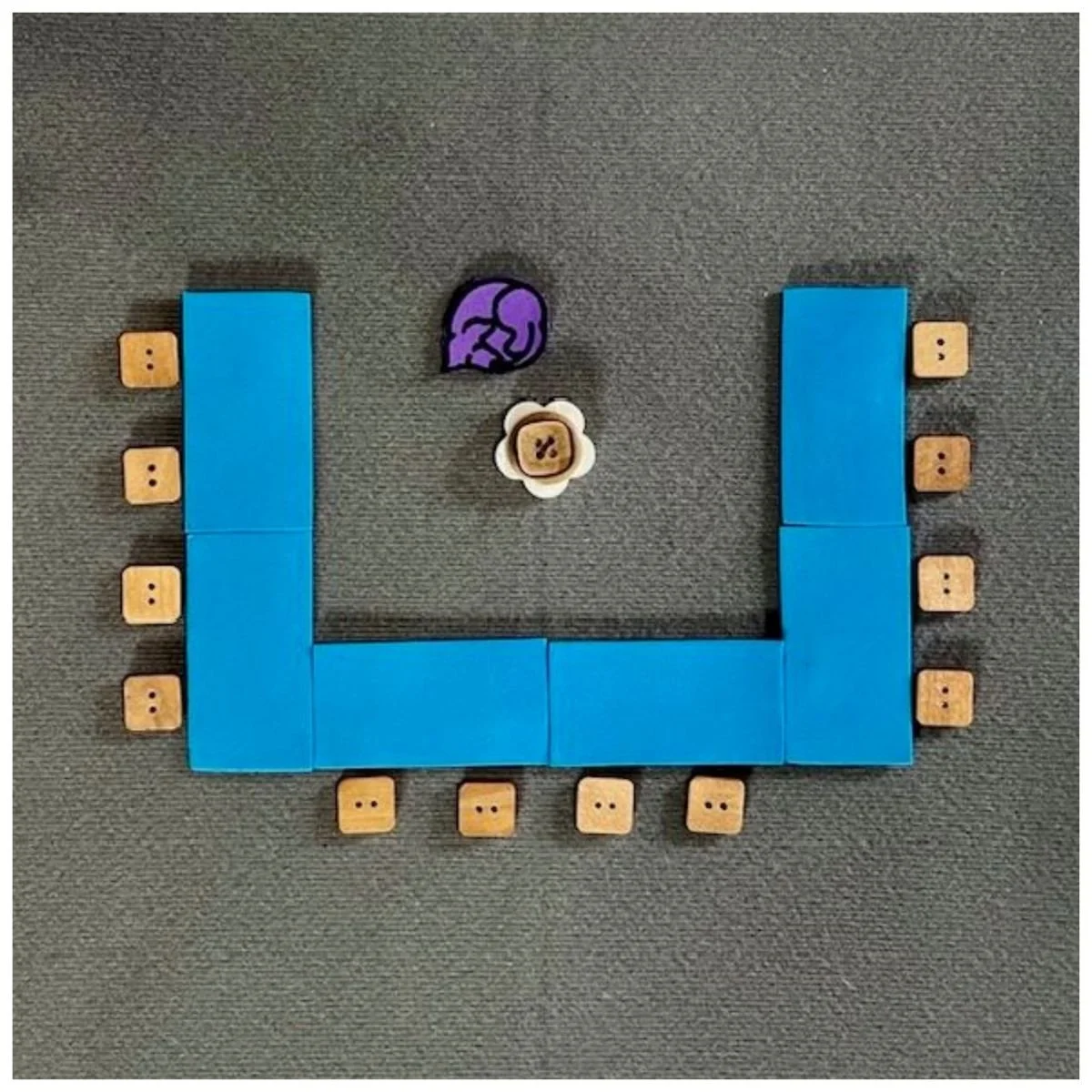 Blue rectangles representing tables set in a u-shape with chairs around the outside. Icons in the center of the u-shape representing a rolling chair and guide dog.