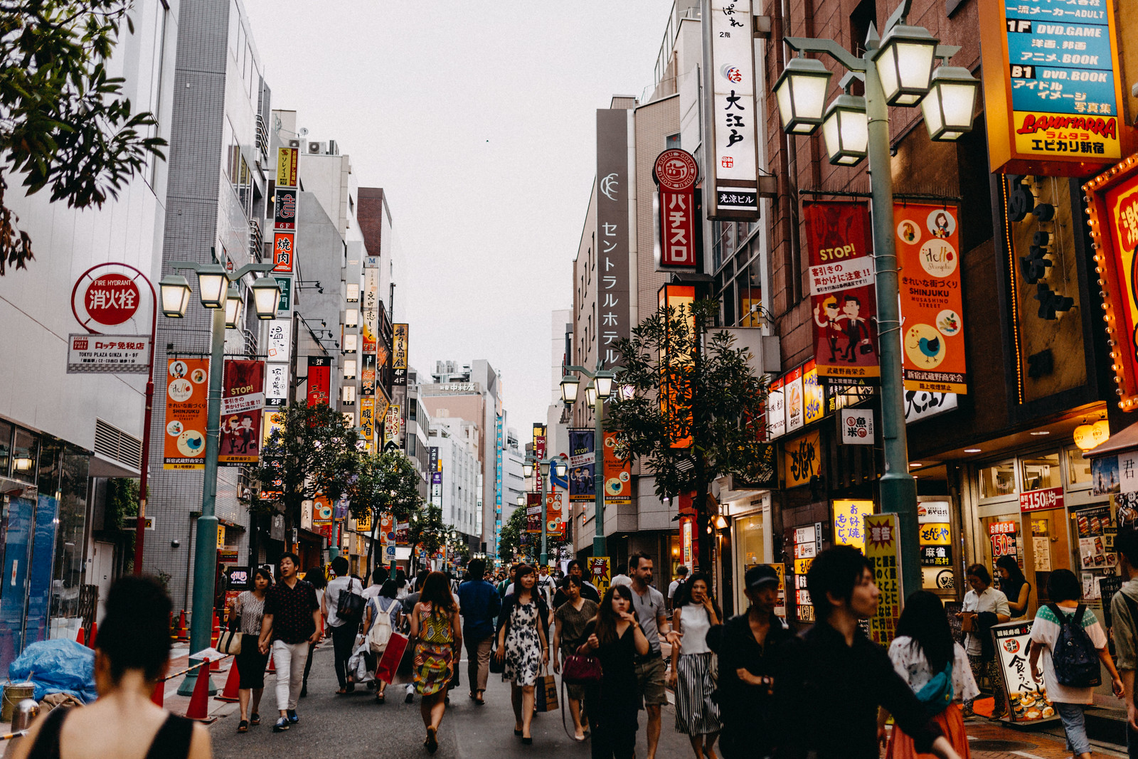 Lit up streets full of people at dusk in Shinjuku Tokyo Japan with restaurants bars and arcades