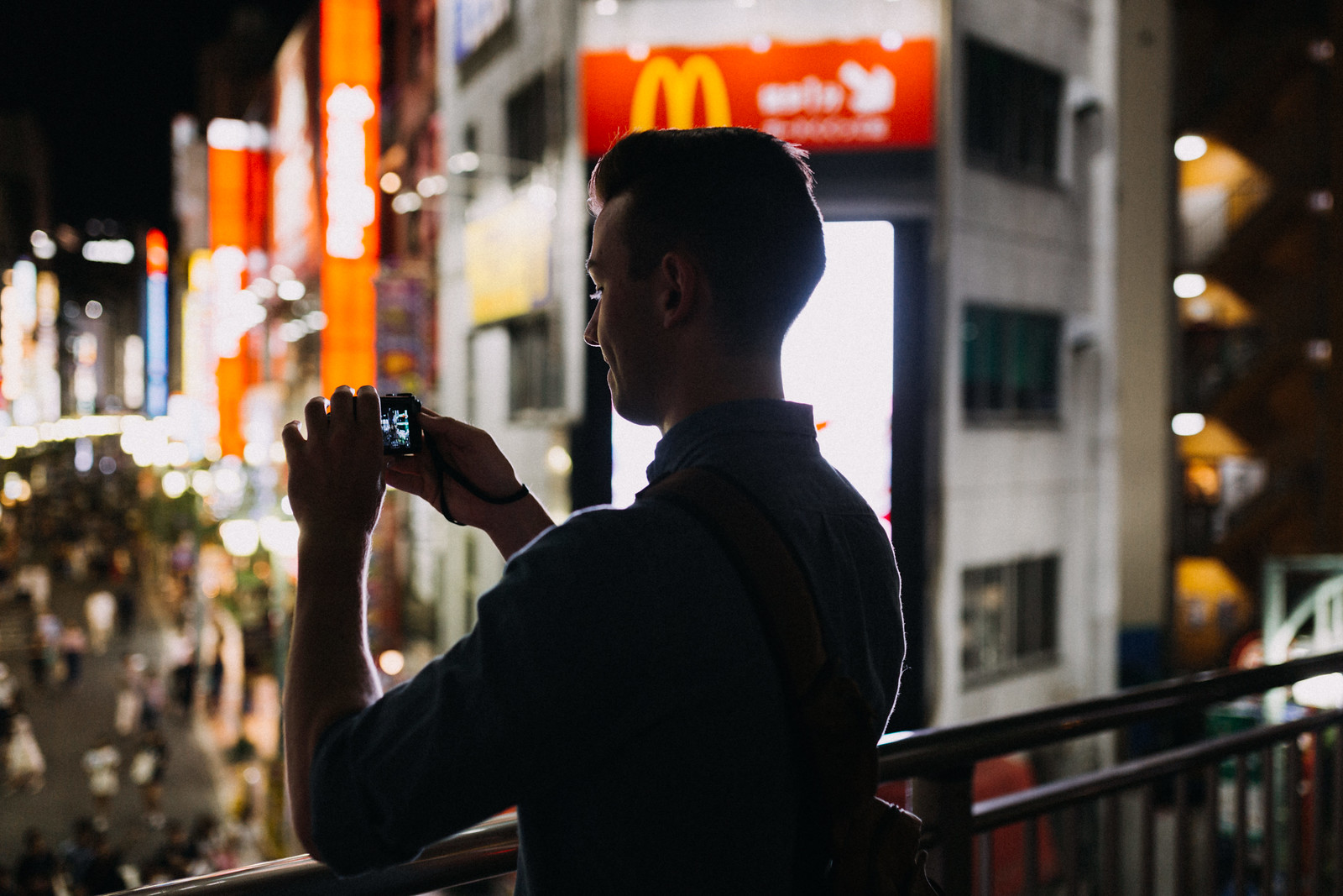 Silhouette of a man taking an iPhone photo in front of a McDonalds in Shinjuku Tokyo Japan