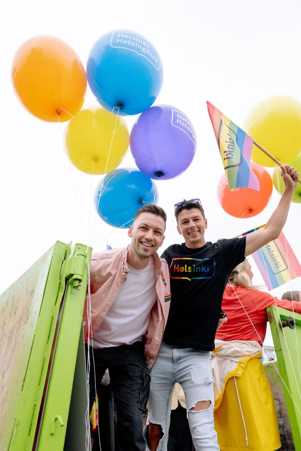 two men pose with baloons and Helsinki flag for Pride.jpeg