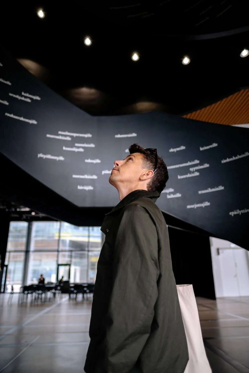 man admiring spiral staircase in Oodi Library with white text.jpeg