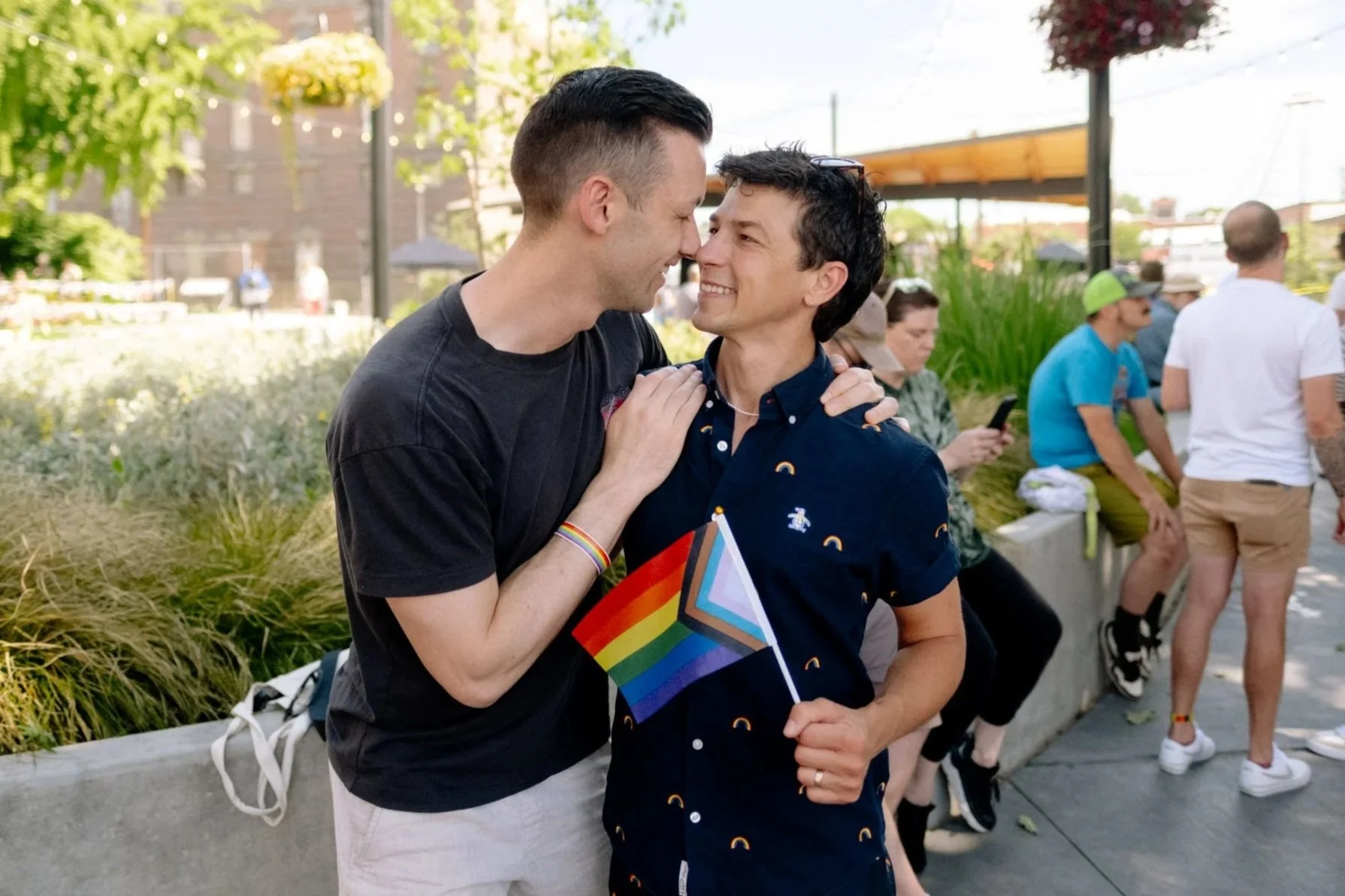 two travelers embrace and hold a pride flag at an LGBTQ+ pride event