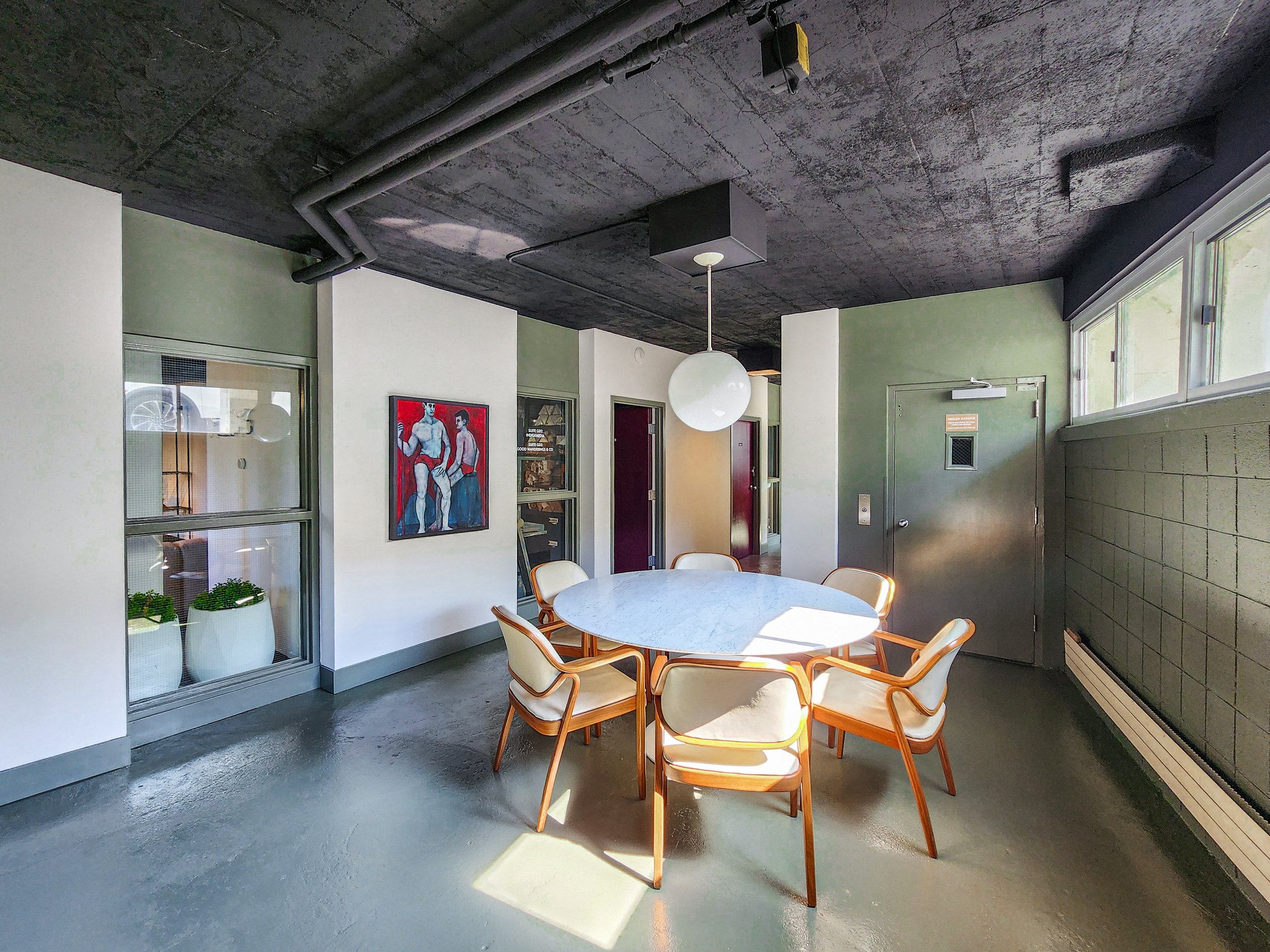 The round table and chairs in the common area, with art and natural light.
