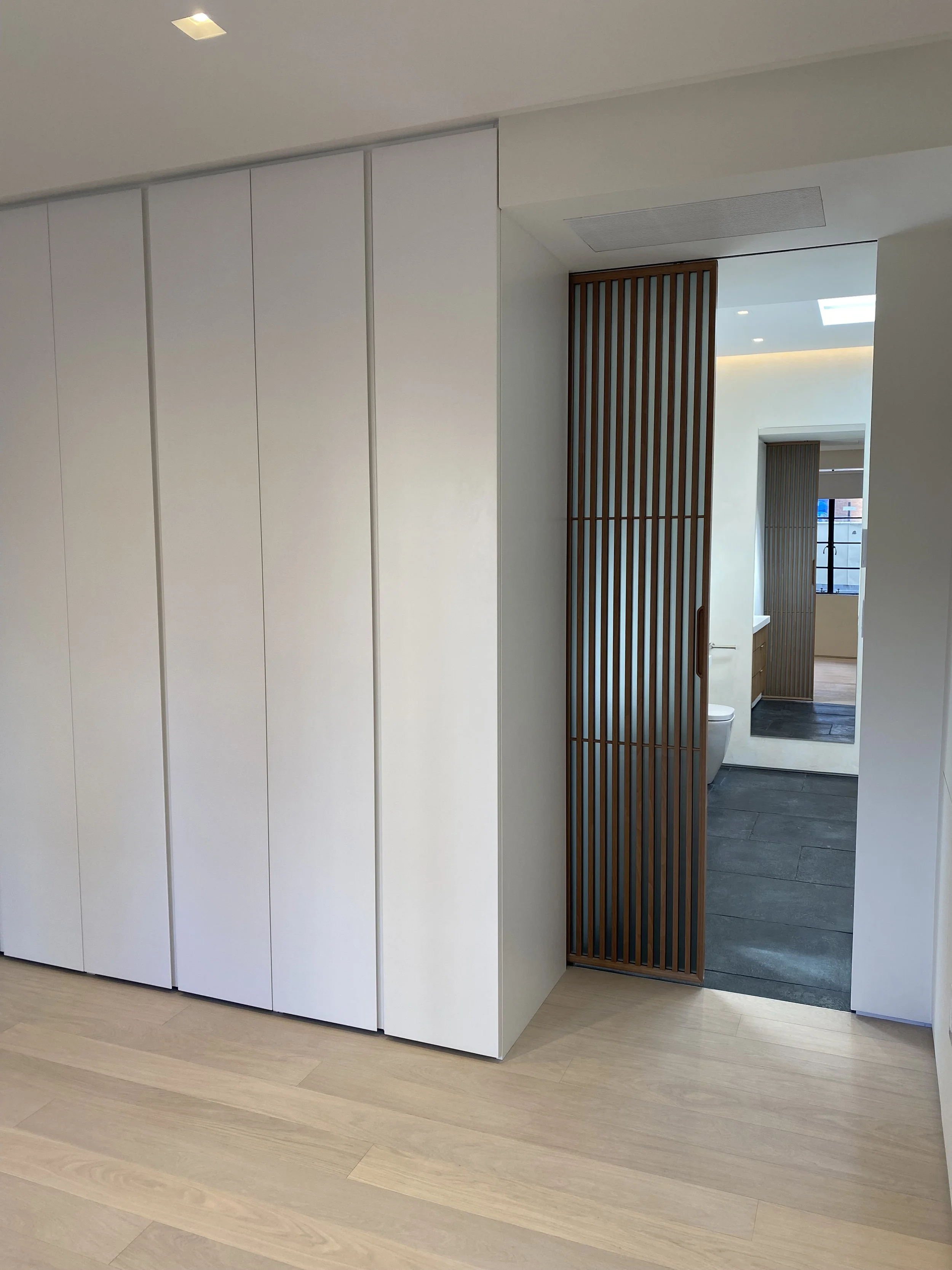  Murray Craft Builders renovated this penthouse apartment with custom closets in the primary bedroom and a sliding pocket door to enter the primary bathroom. 