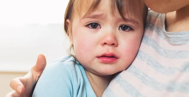 A tearful toddler being comforted by a loving caregiver.