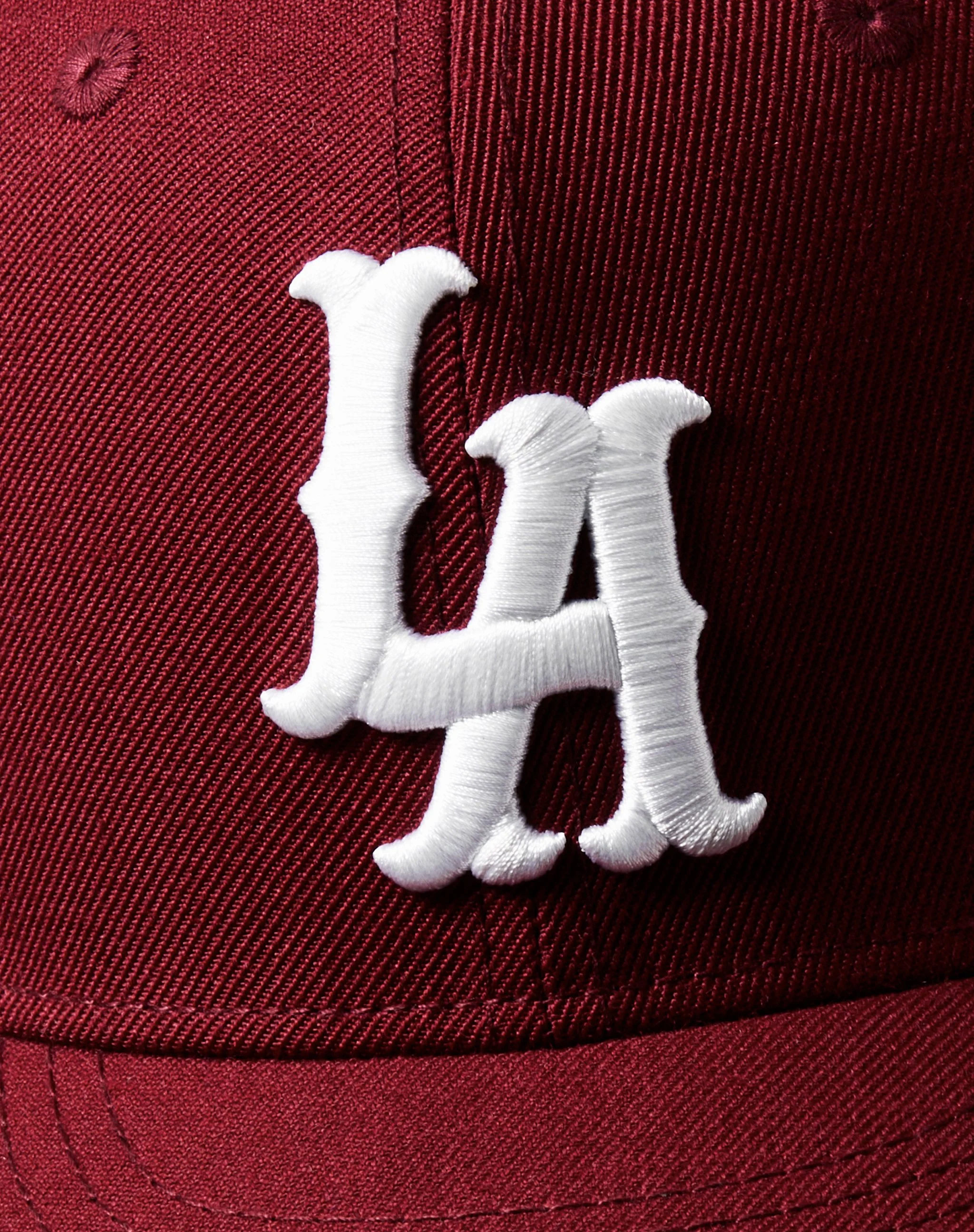 Close-up of a red fabric cap with a white embroidered dog applique on the front.