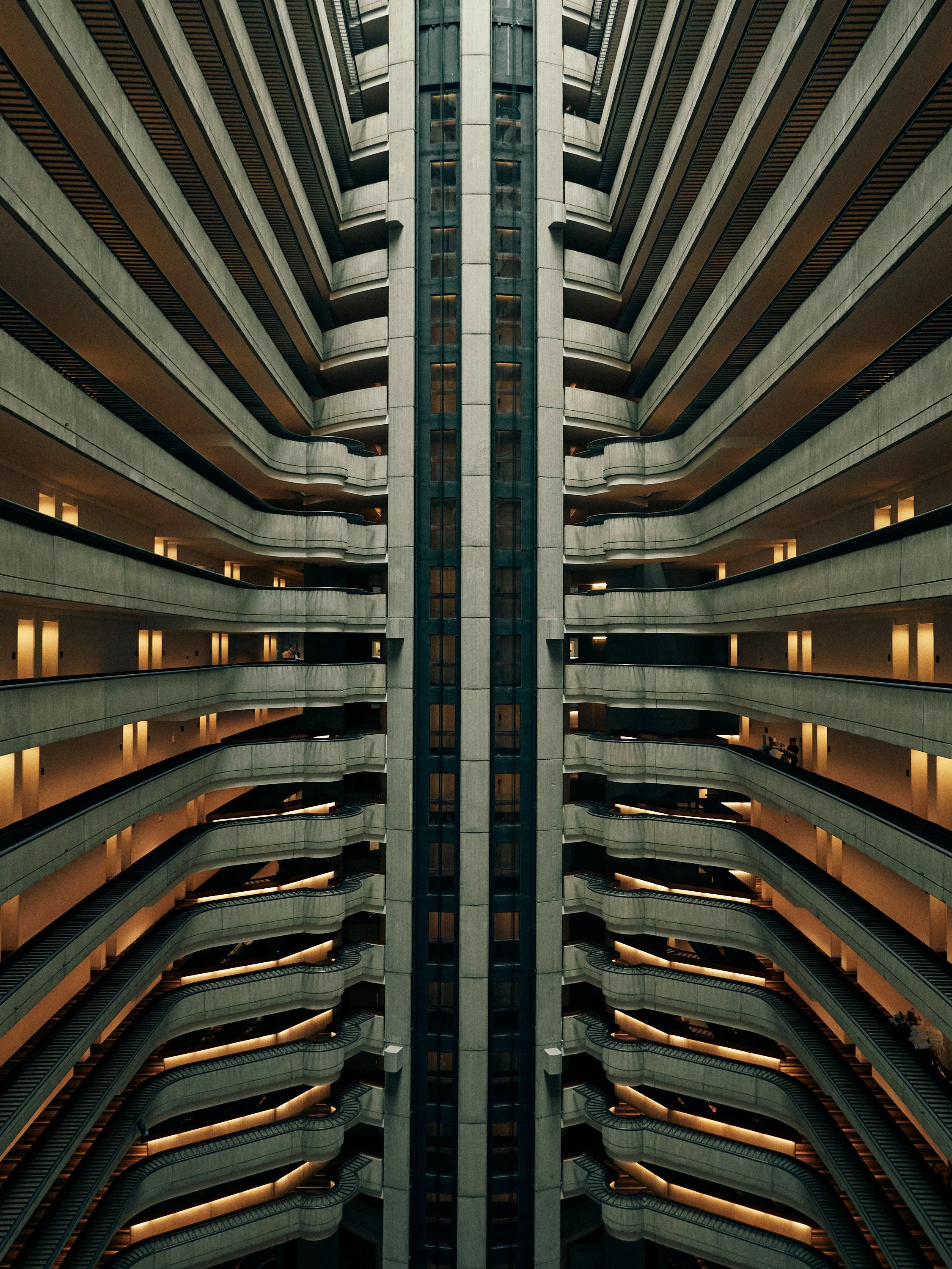 A tall, multi-level indoor parking garage with curving balconies and railings, illuminated by yellow lighting.