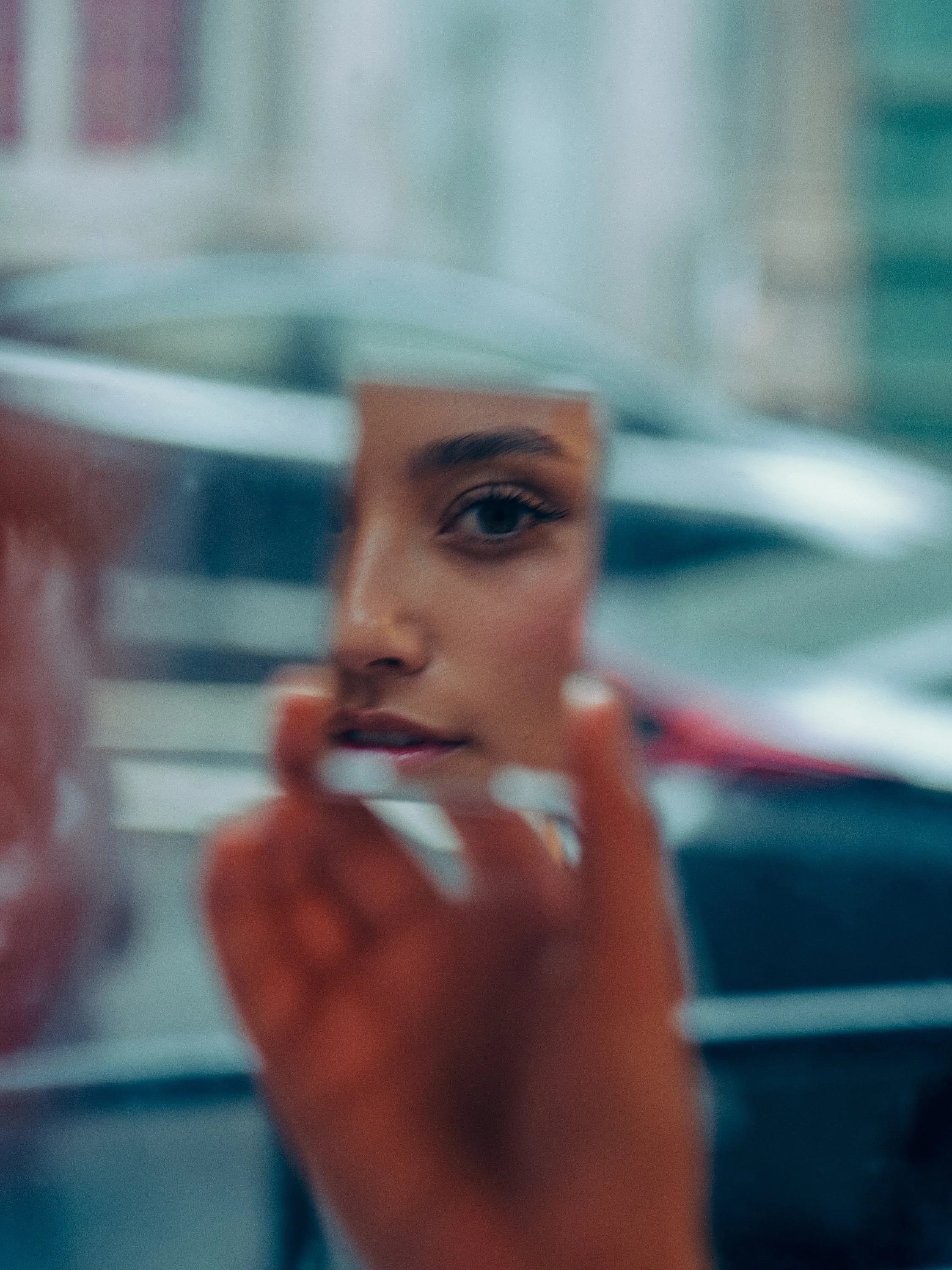 A person is looking through a glass window, with part of their face visible on the other side, holding a book or notebook.