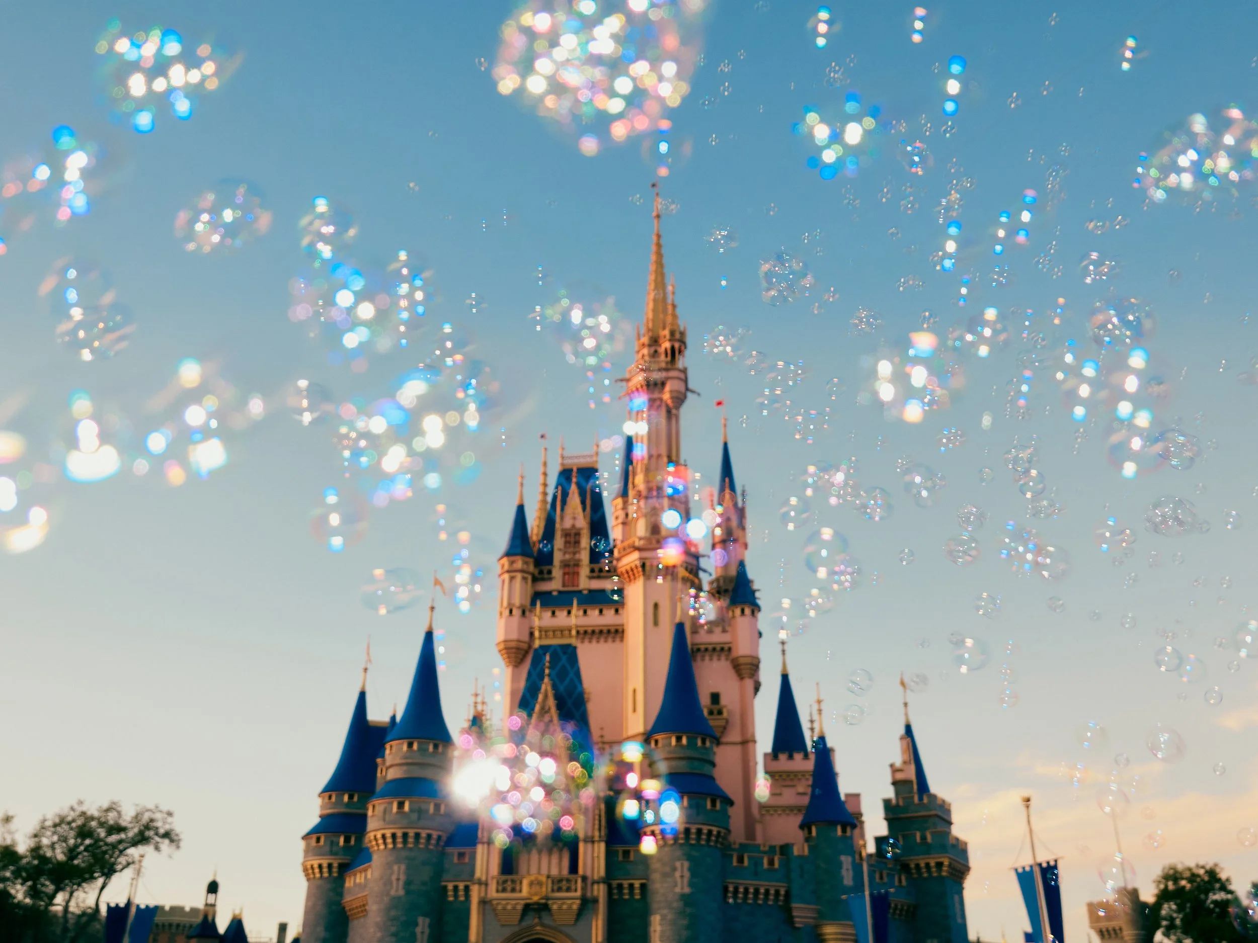 Disney castle at sunset with sparkling glitter in the air.