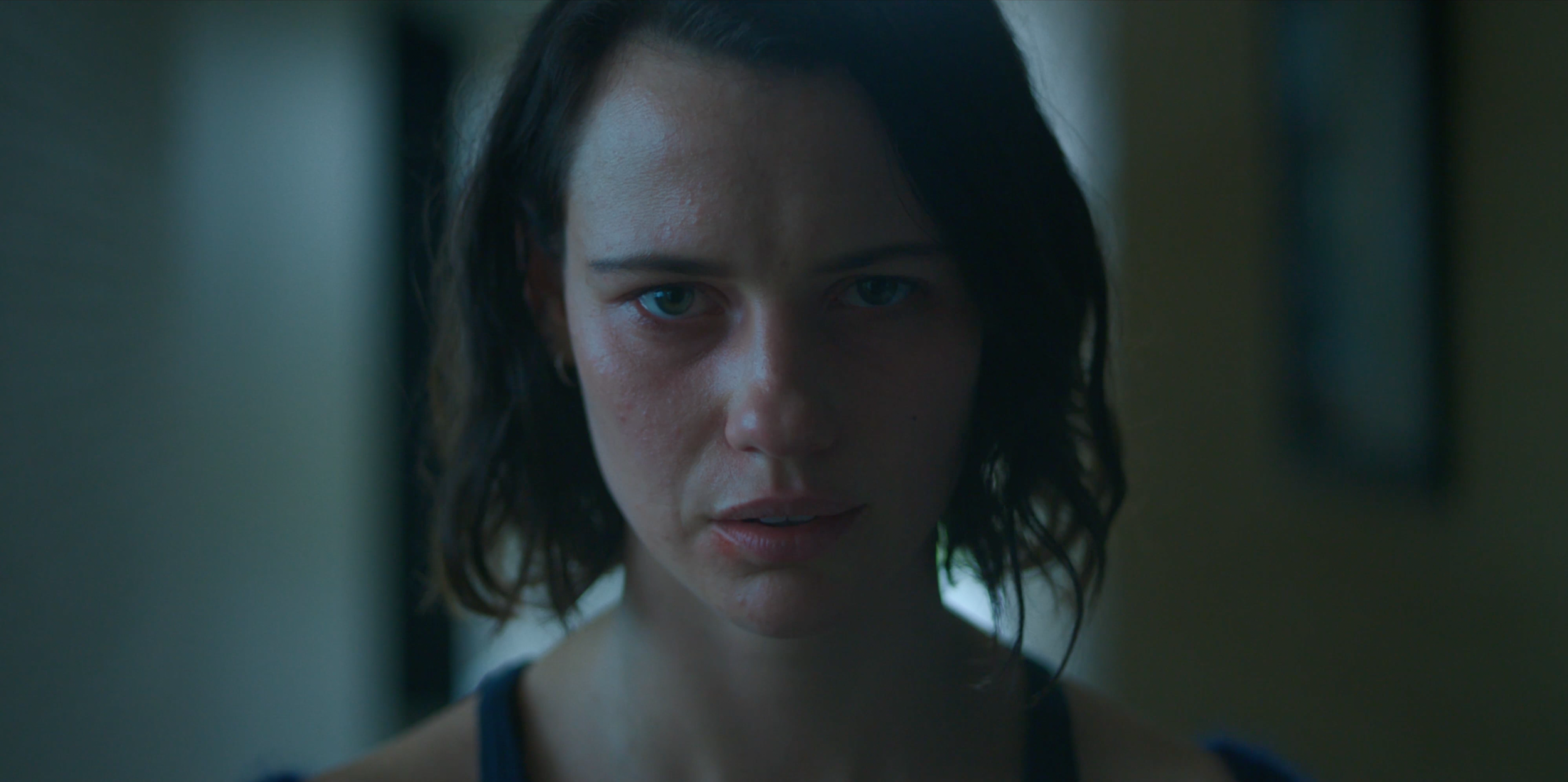 Tight front-on close-up of Lily Sullivan in Monolith, breaking the film's earlier distance as the character loses her grip.