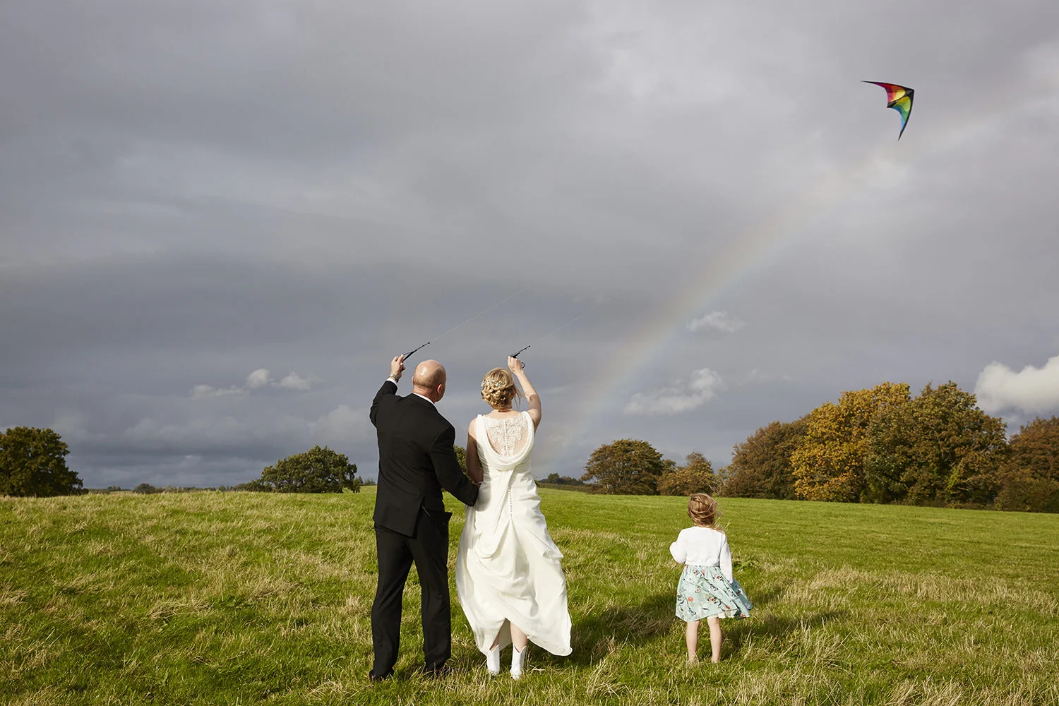 Bride and Groom flying a kite with a rainbow sky, Monks Withecombe