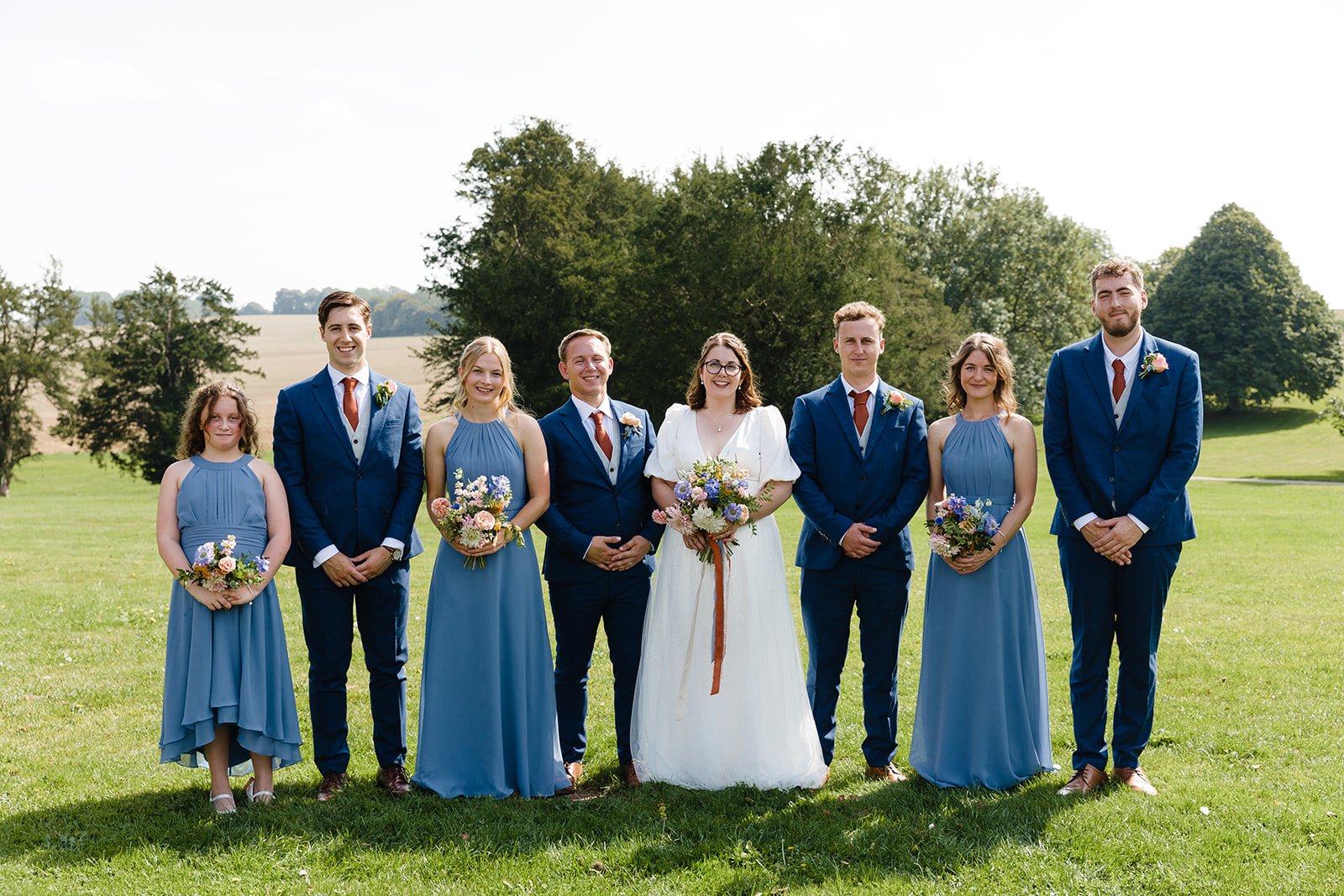 A groups shot of a wedding party against a backdrop of luscious rolling hills