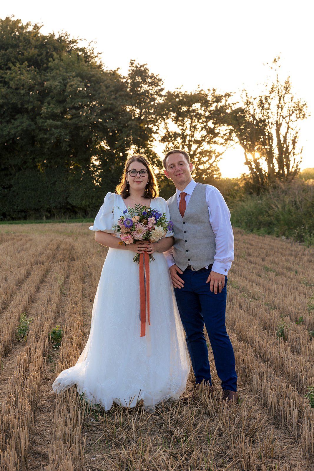 Newlywed couple photographed in a field in the golden evening light