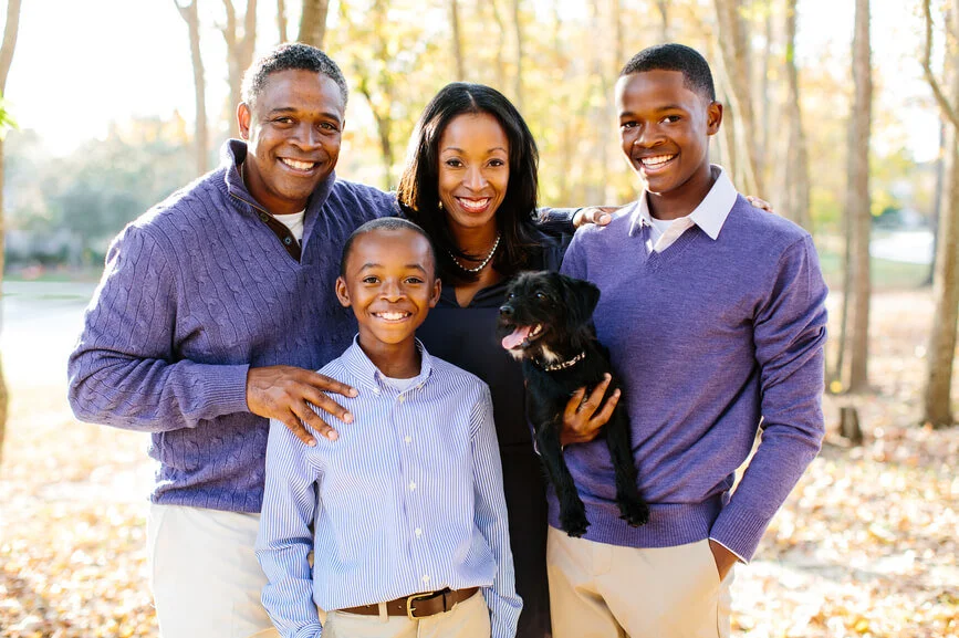 Happy family with their dog standing outside their new home after buying a house in Washington DC, Maryland, or Northern Virginia