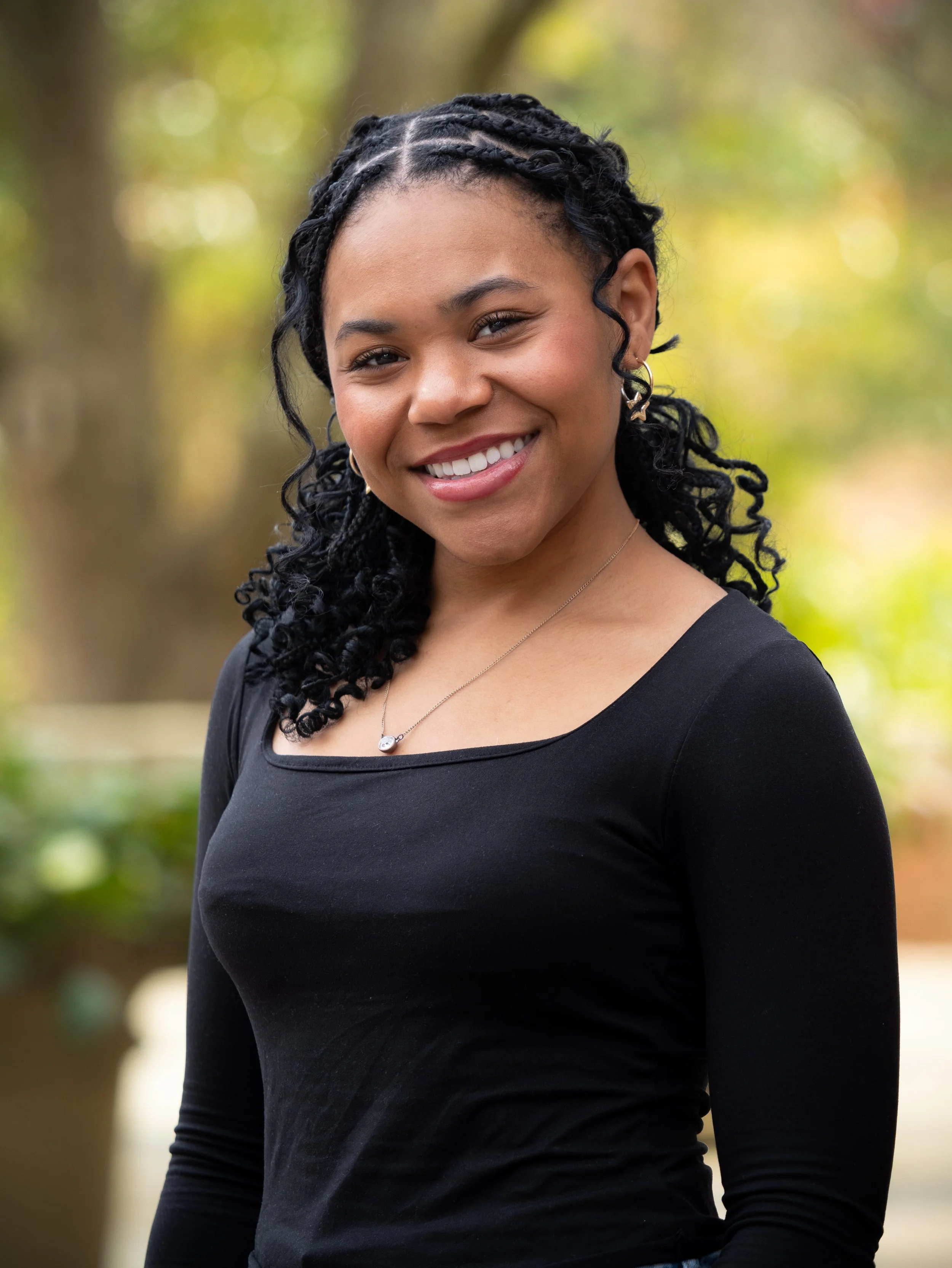 A woman standing for a portrait against a outdoor backdrop
