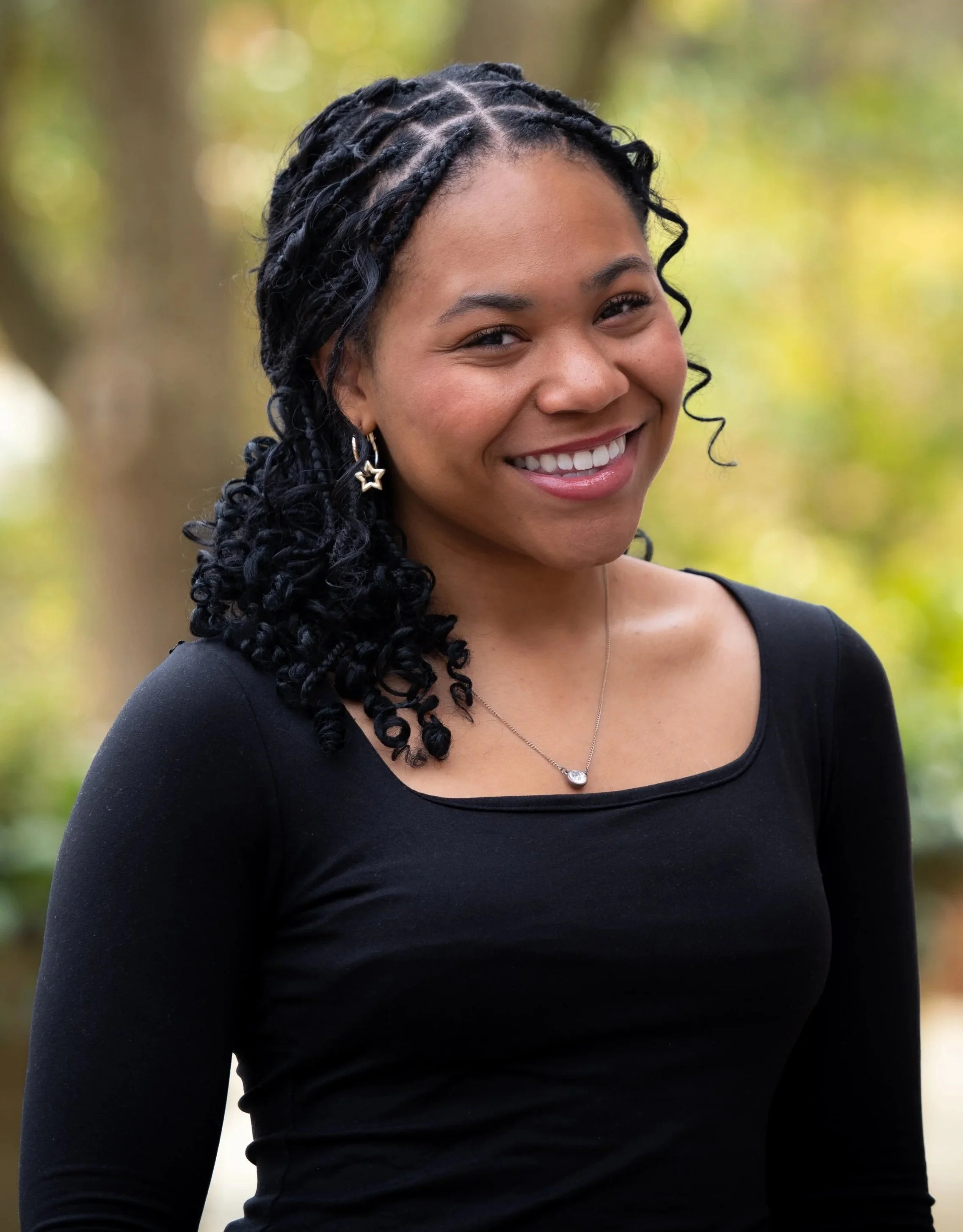 A woman standing for a portrait against a outdoor backdrop