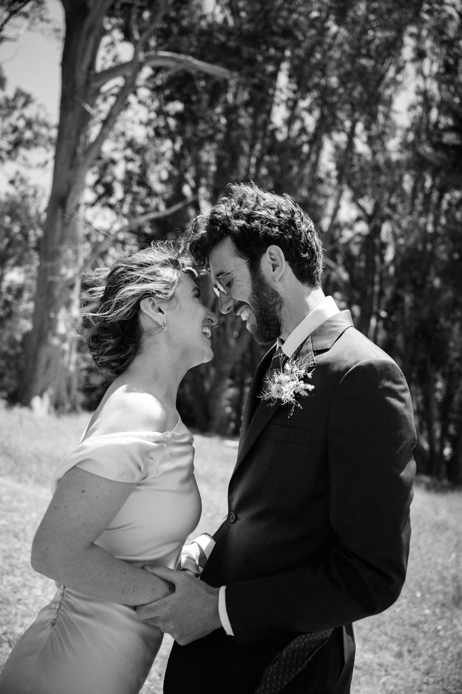 A bride and group looking at each other, nose to nose, laughing and holding hands. Black & White.