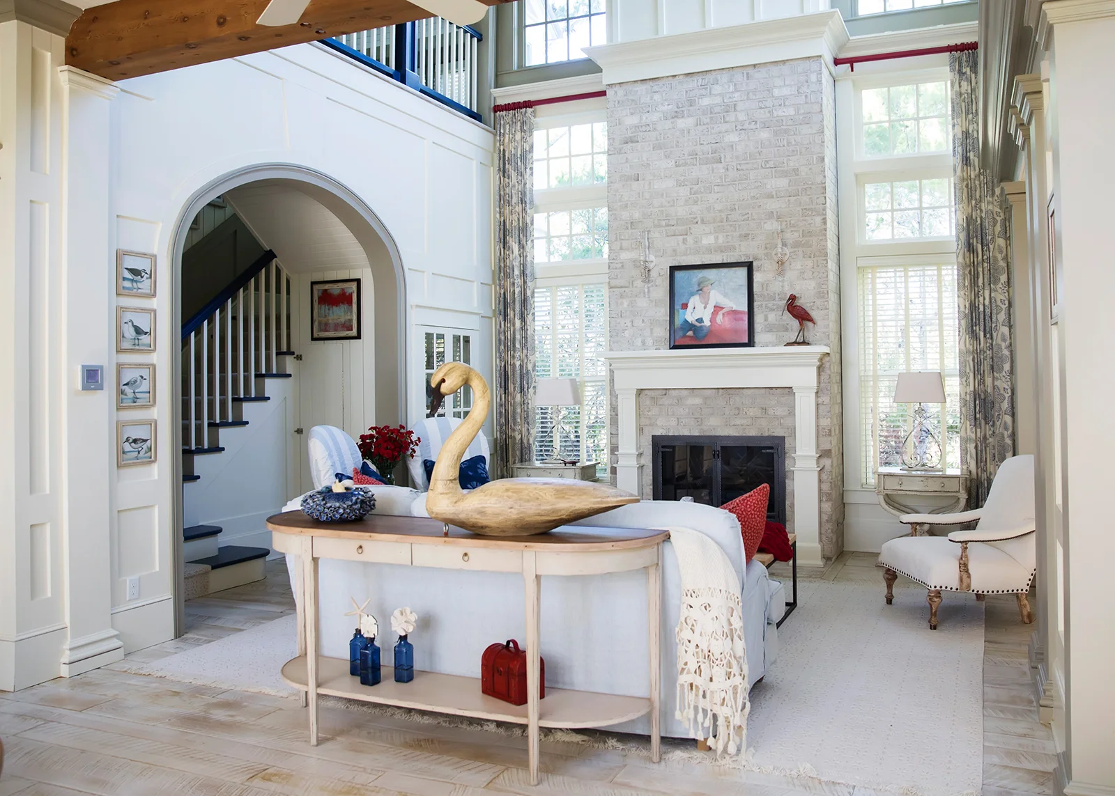 A casual slipcovered sofa, two striped side chairs, a traditional tight-back upholstered arm chair, rustic console table, stylish end tables, metal lamps, paisley draperies and creme-colored area rug lend a cohesive look to eclectic pieces. Resources: Sofa: VanGuard with Miles Talbot “Washed Turks” fabric Side Chairs: Hickory Chair with Miles Talbot “Washed Caicos” fabric Accent Chair: CR Laine with Robert Allen “Dignified” fabric Console Table: Century Furniture Throw: Pottery Barn Side Tables: Habersham Lamps: Visual Comfort Area Rug: Nourisan “Grosse Point” Drapery Fabric: Lee Jofa “Medina” Design Thought: Console tables placed behind a floating sofa can delineate spaces in an open floor plan.